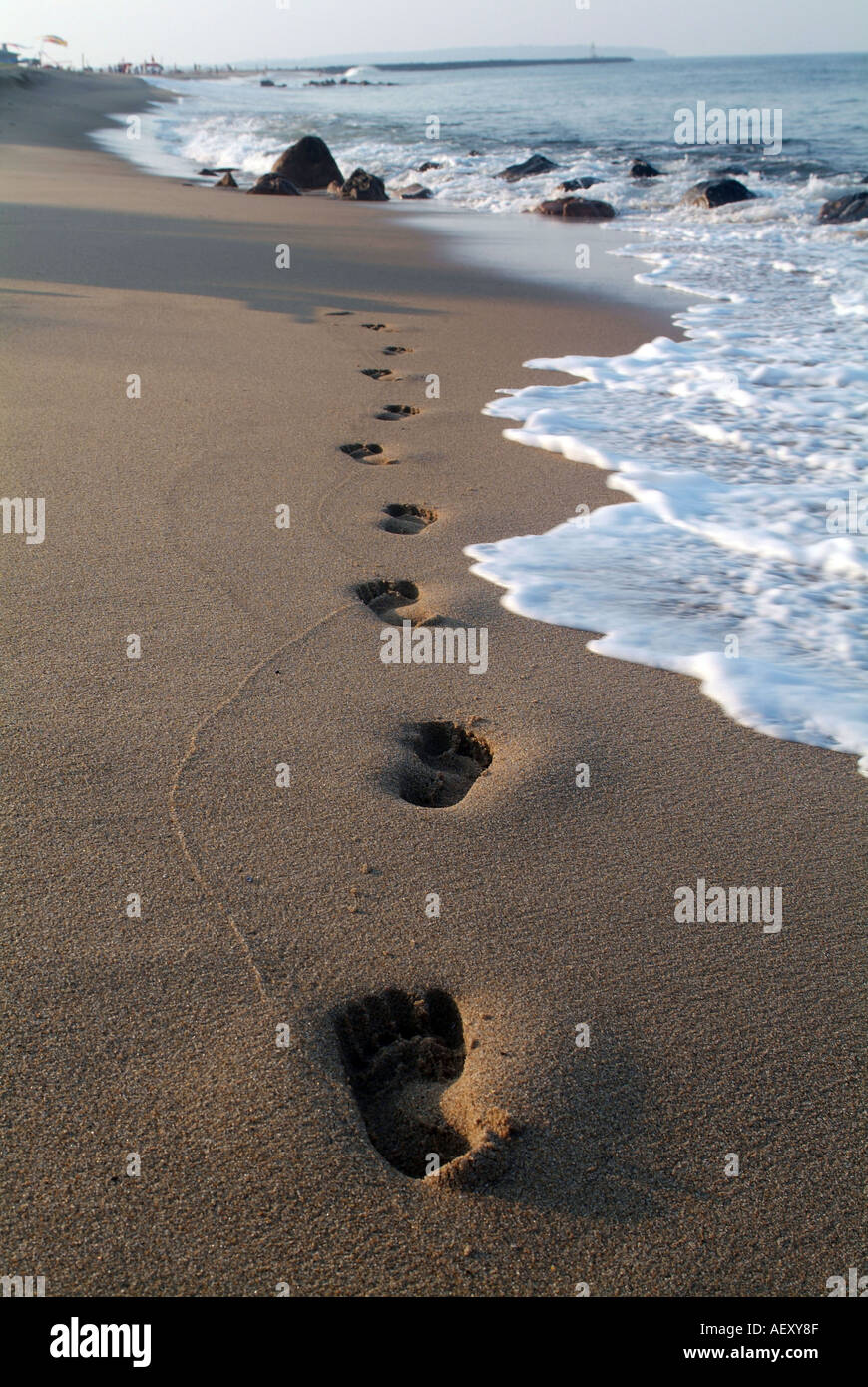 Footprints on sand at beach with waves and ocean Stock Photo