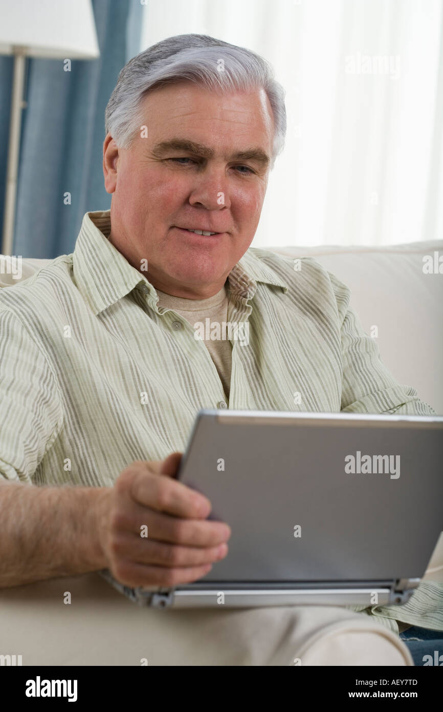 Senior man using laptop on sofa Stock Photo