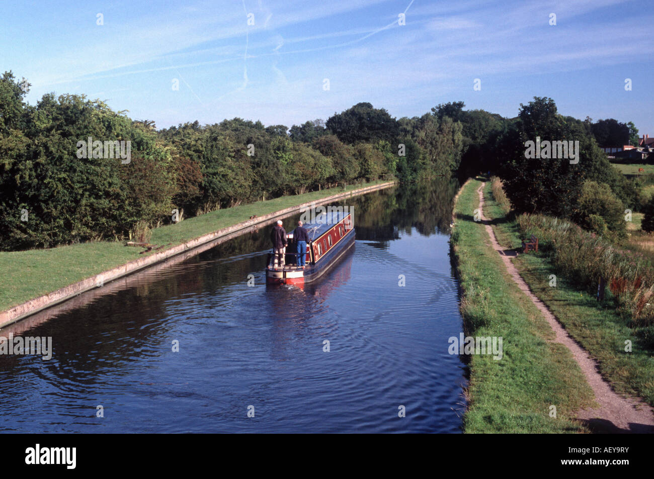 Two men on stern of narrowboat approaching Brewood on the Shropshire Union Canal, south Staffordshire, England Stock Photo