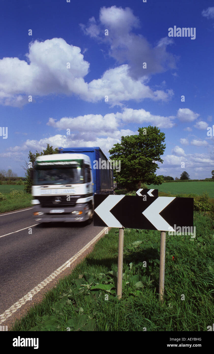 lorry travelling on country road passing warning chevron signs of bend