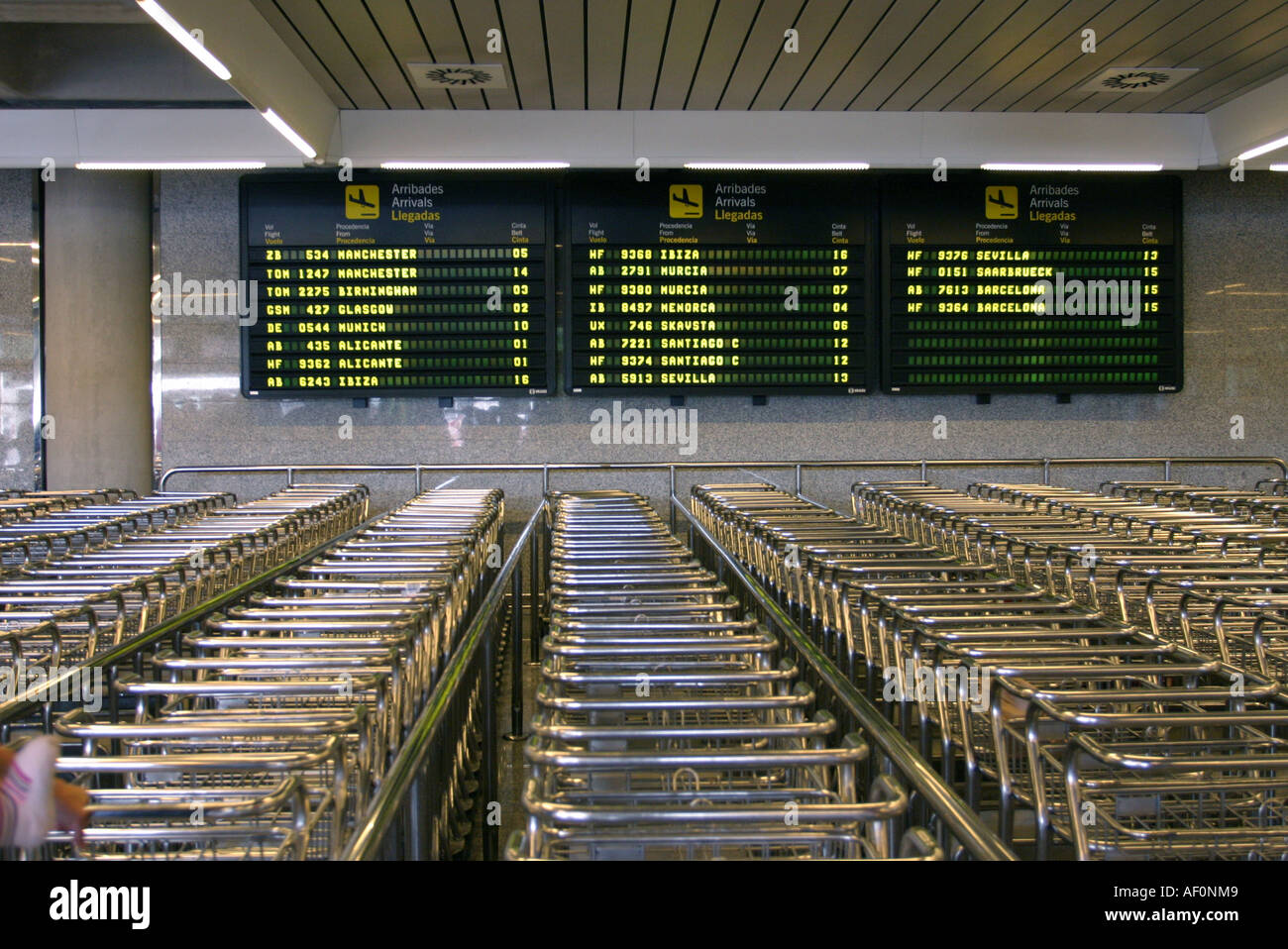 Baggage wagons in front of the arrivals board at Palma Airport Mallorca Spain Stock Photo