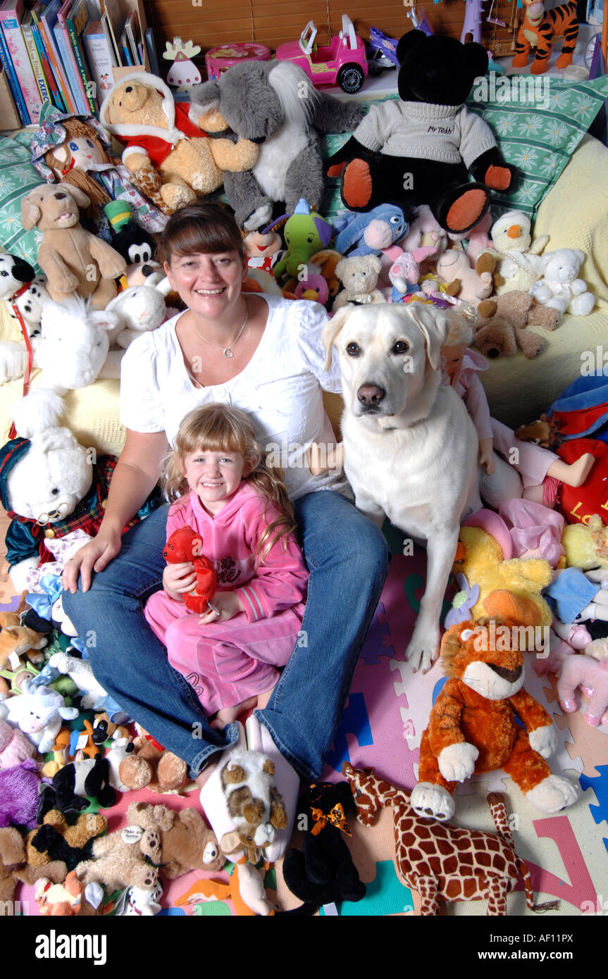 Smiling brunette mother and five year old blonde daughter with soft toys and pet dog Stock Photo