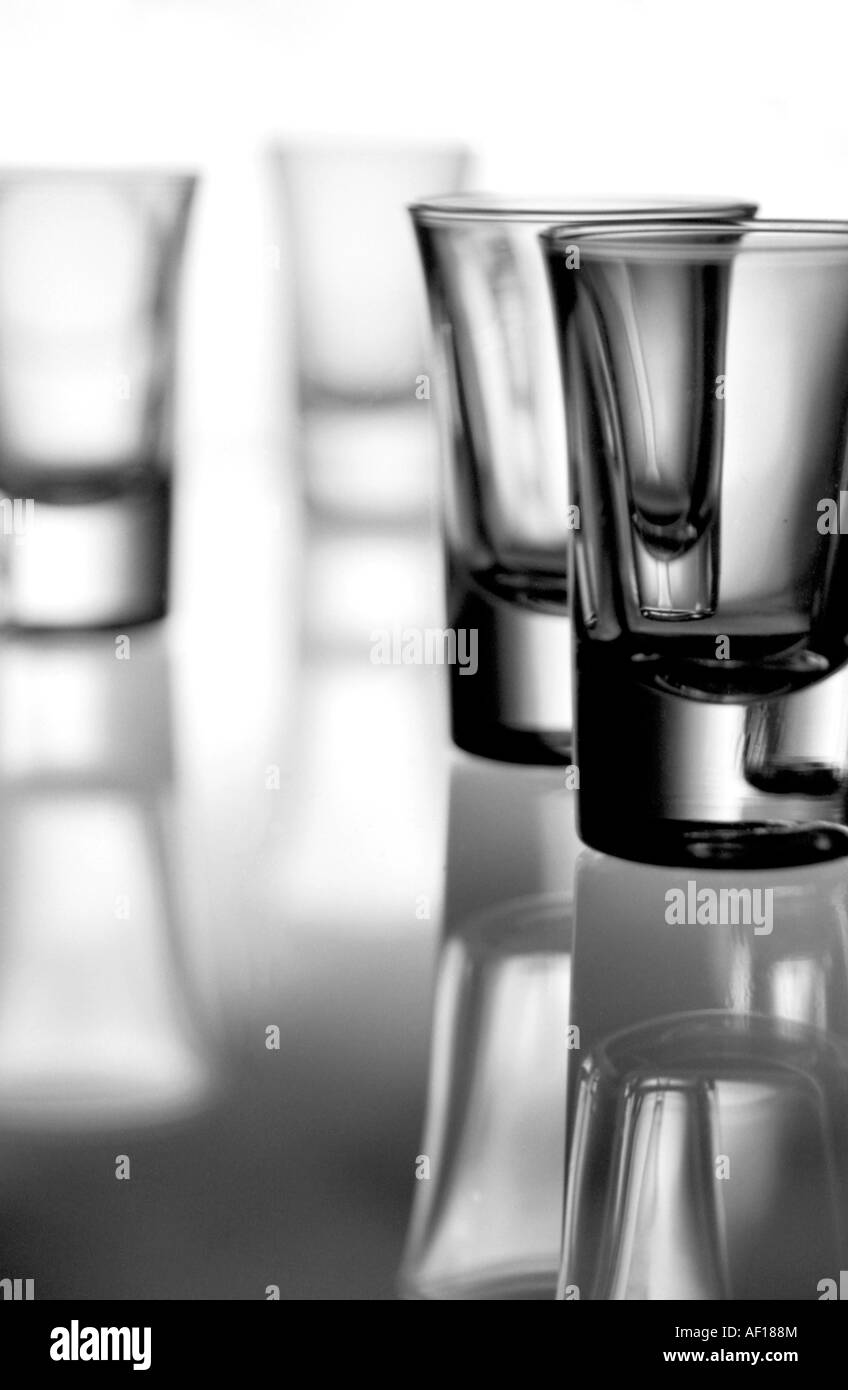 A set of shot glasses reflecting on a glass table Stock Photo Alamy