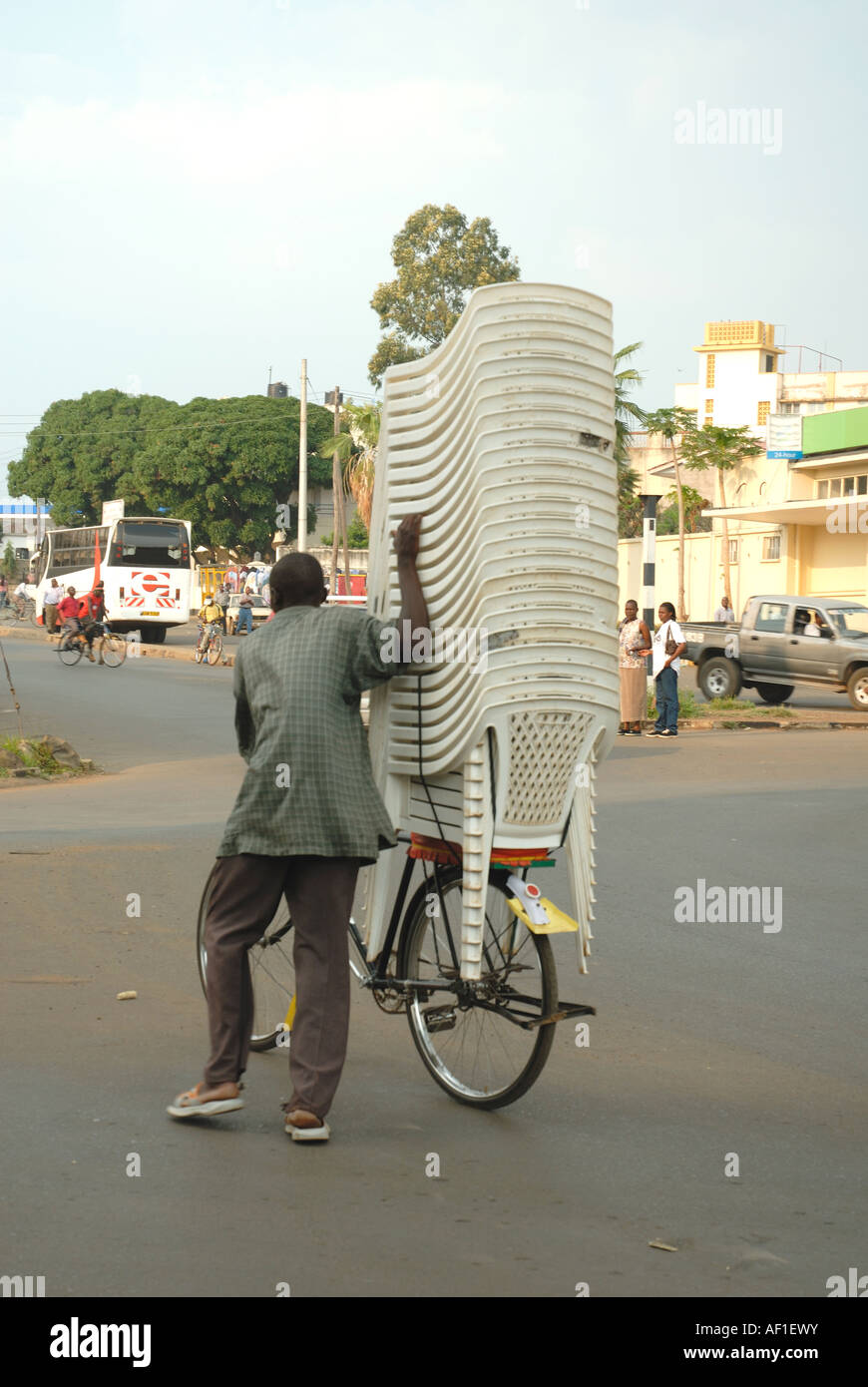 Luo man pushing a bicycle heavily loaded with a towering pile of