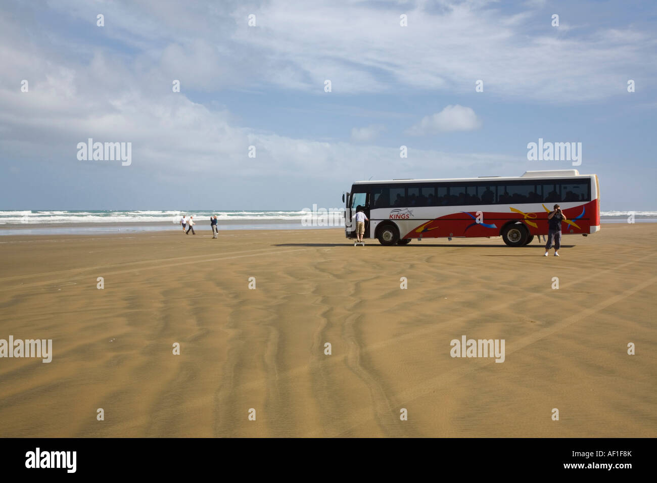 Remote Ninety Mile Beach with tourists and parked coach by Tasman Sea on west coast Aupori Peninsula North Island New Zealand Stock Photo