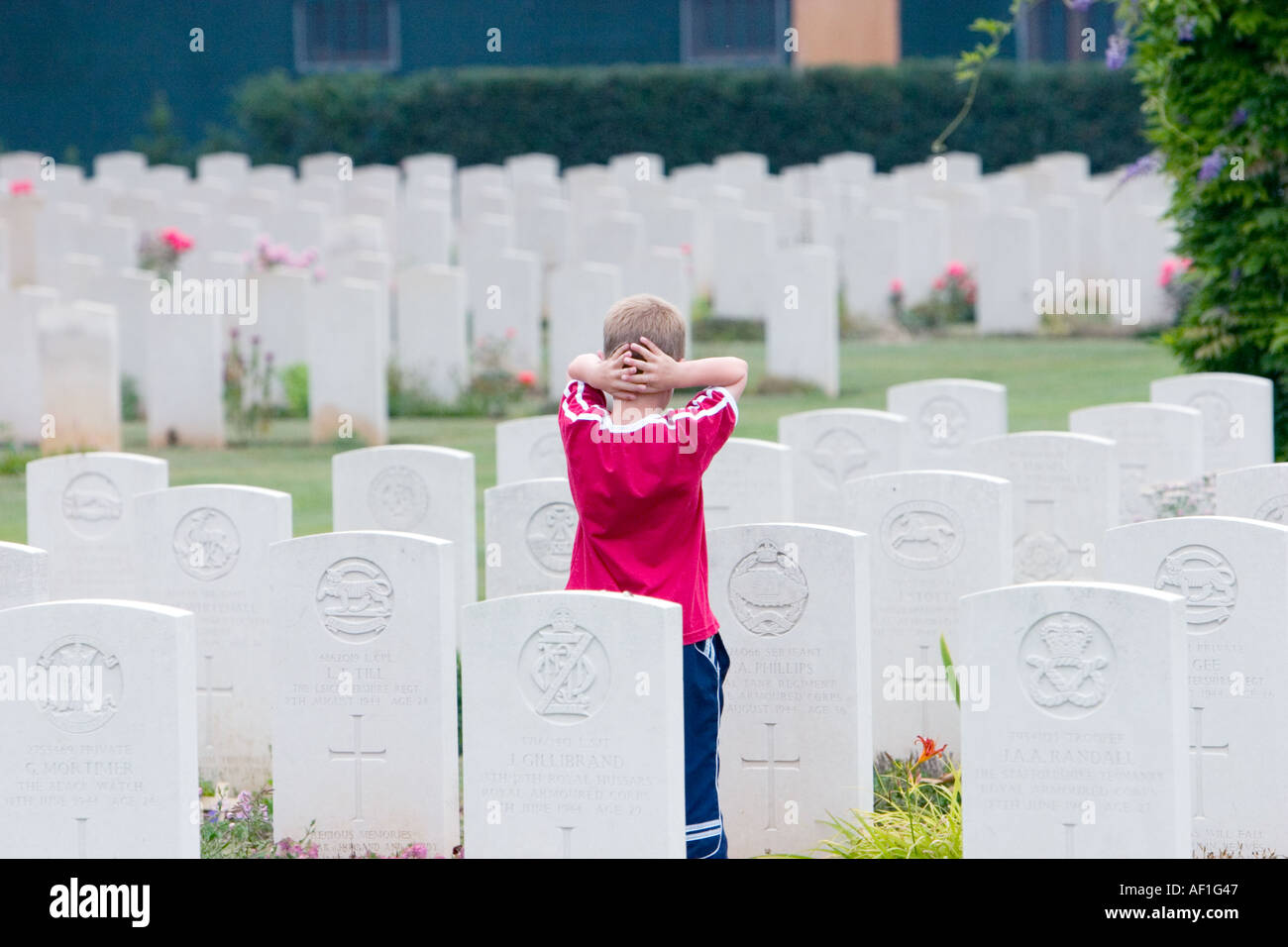 A small child contemplating grave of fallen serviceman killed during fight to liberate France from German occupation WW2 Stock Photo