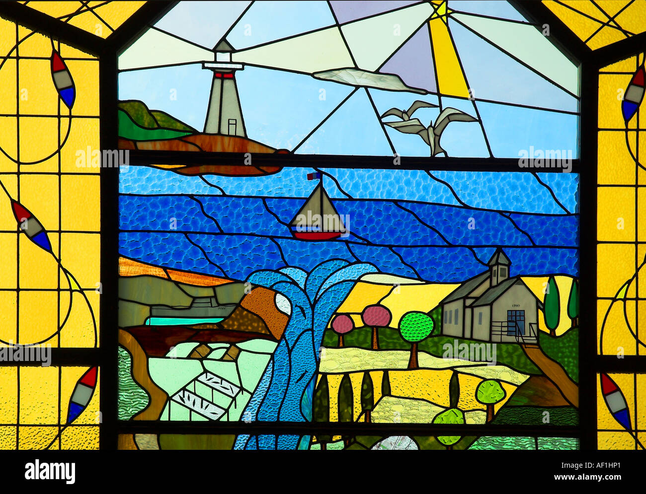A stained glass window showing a seaside village scene in an old chapel in Quebec Stock Photo