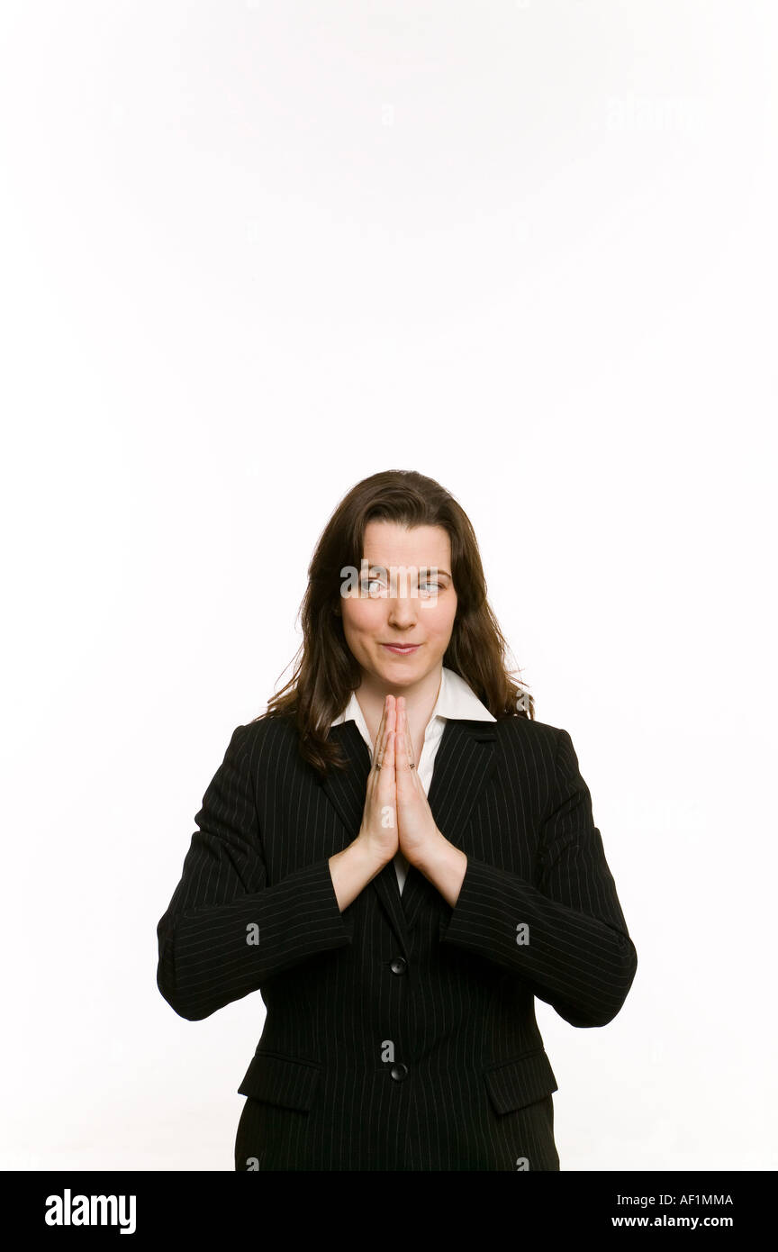 business woman in dark suit praying and glancing to side Stock Photo