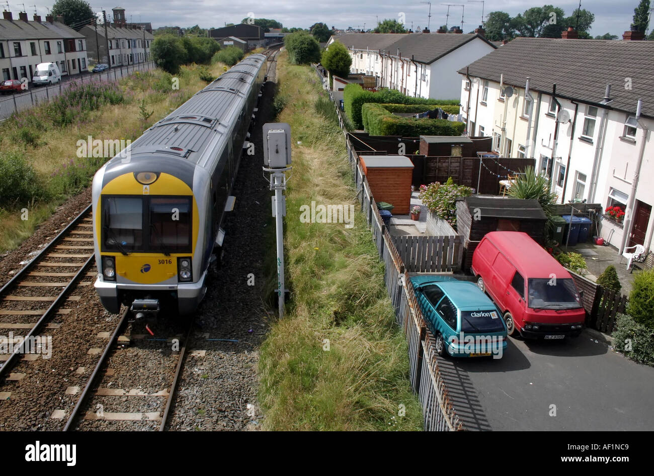 Diesel train on railway running next to terraced row of houses, Lurgan, County Armagh, Northern Ireland Stock Photo