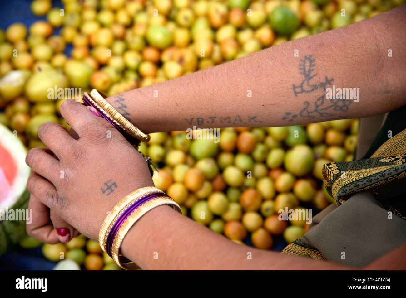Close up of arm tattoos of Indian tribal female purchasing ber fruit, Vanakbara Fishing Village, Diu Island, Gujarat, India Stock Photo