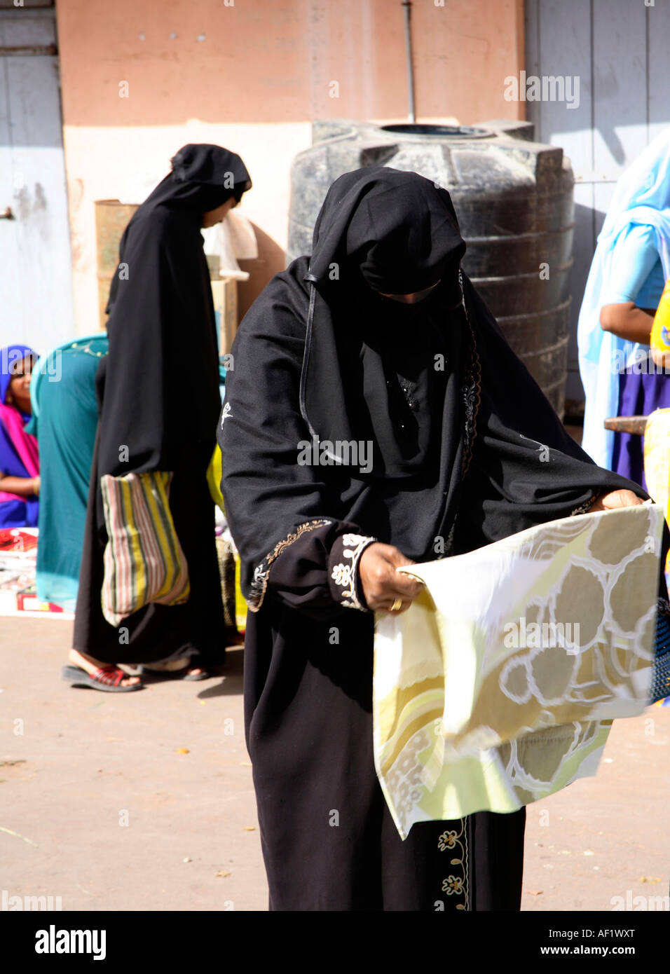 Indian muslim female wearing niqab shopping for material at stall in market, Vanakbara Fishing Village, Diu Island, Gujarat, India Stock Photo
