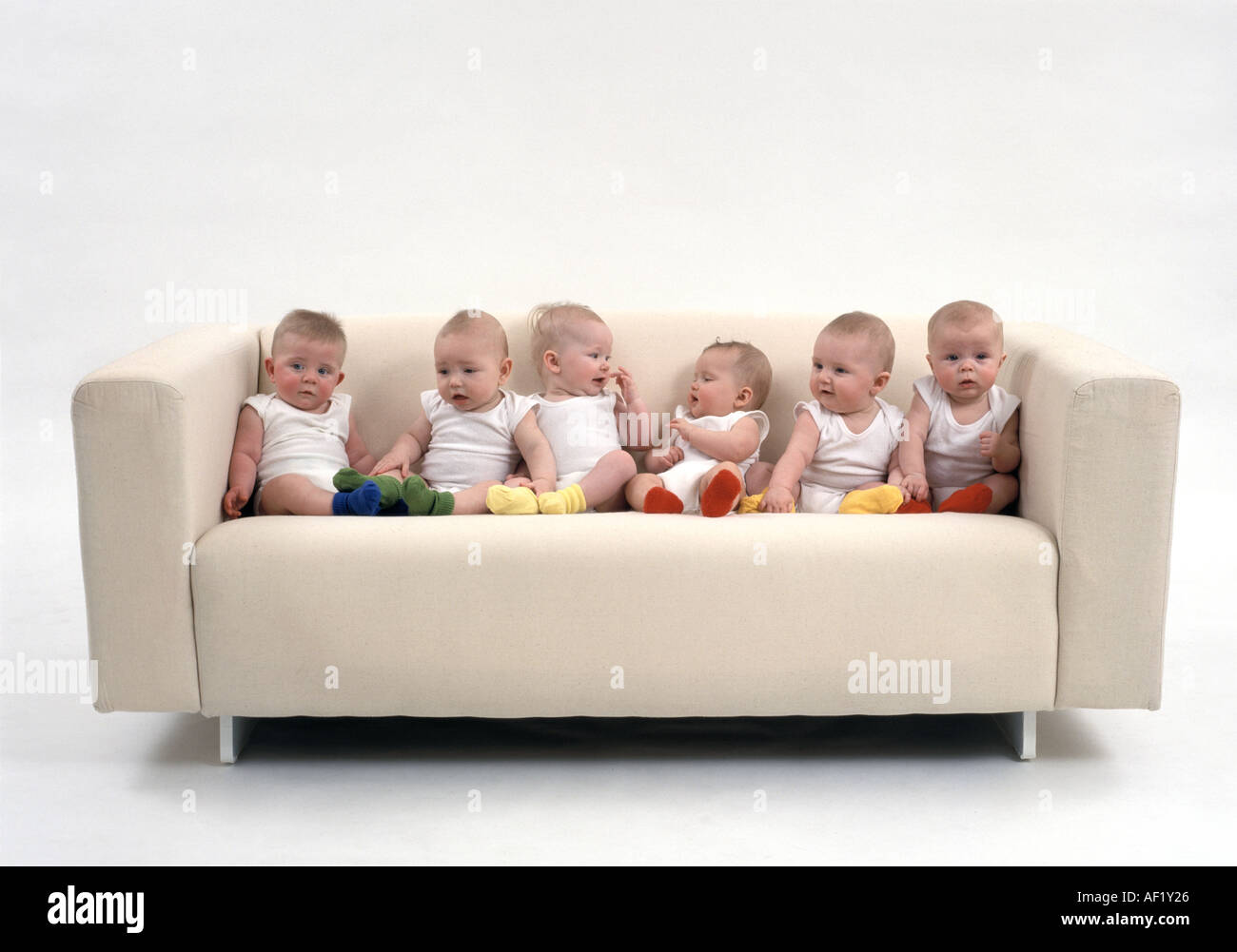 Six babies sitting on a sofa Stock Photo