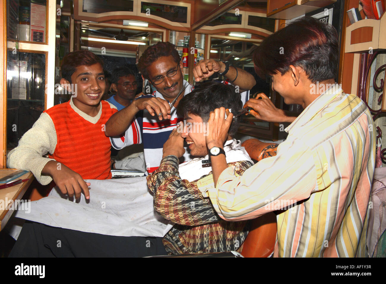 Indian man has barbers cutting hair from both sides, Dwarka, Gujarat