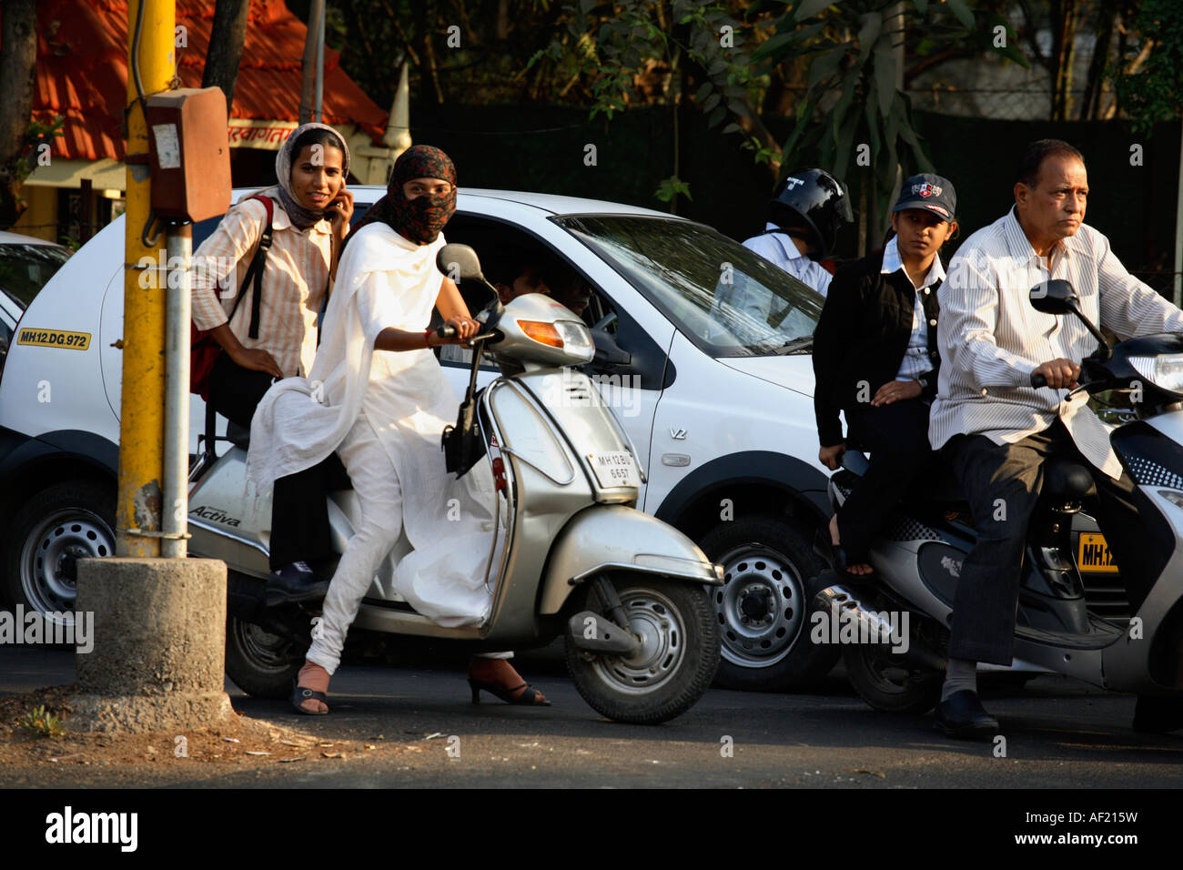 Young Indian female driving scooter without helmet wearing salwaar kameez in busy traffic, Pune
