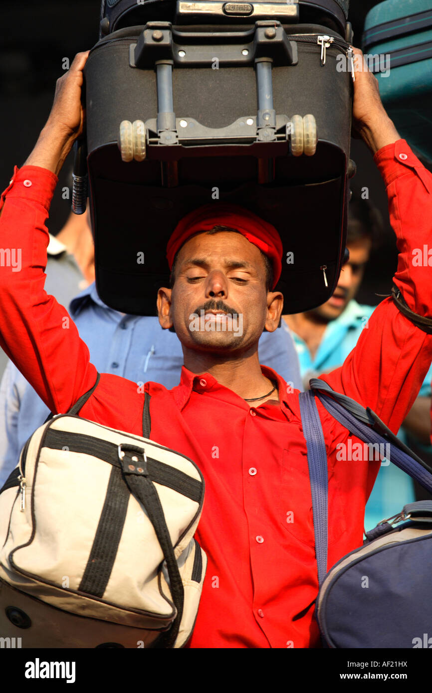 Indian Porter carrying suitcase on head at railway station, Pune, India Stock Photo