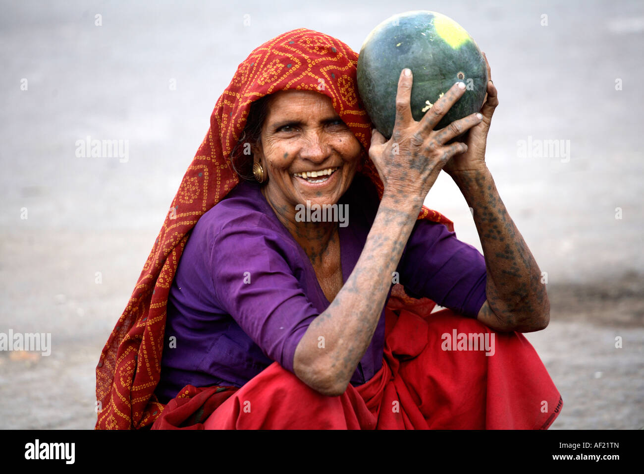 Rabari tribal female with neck, arm and hand tattoos selling water melons at market stall, Una, Gujarat, India Stock Photo