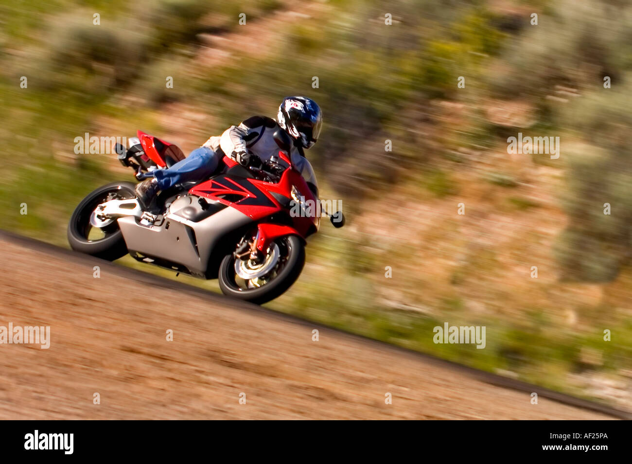 Bullet sport bike corners in a canyon with red rock in the background in this shot with plenty of motion blur Stock Photo