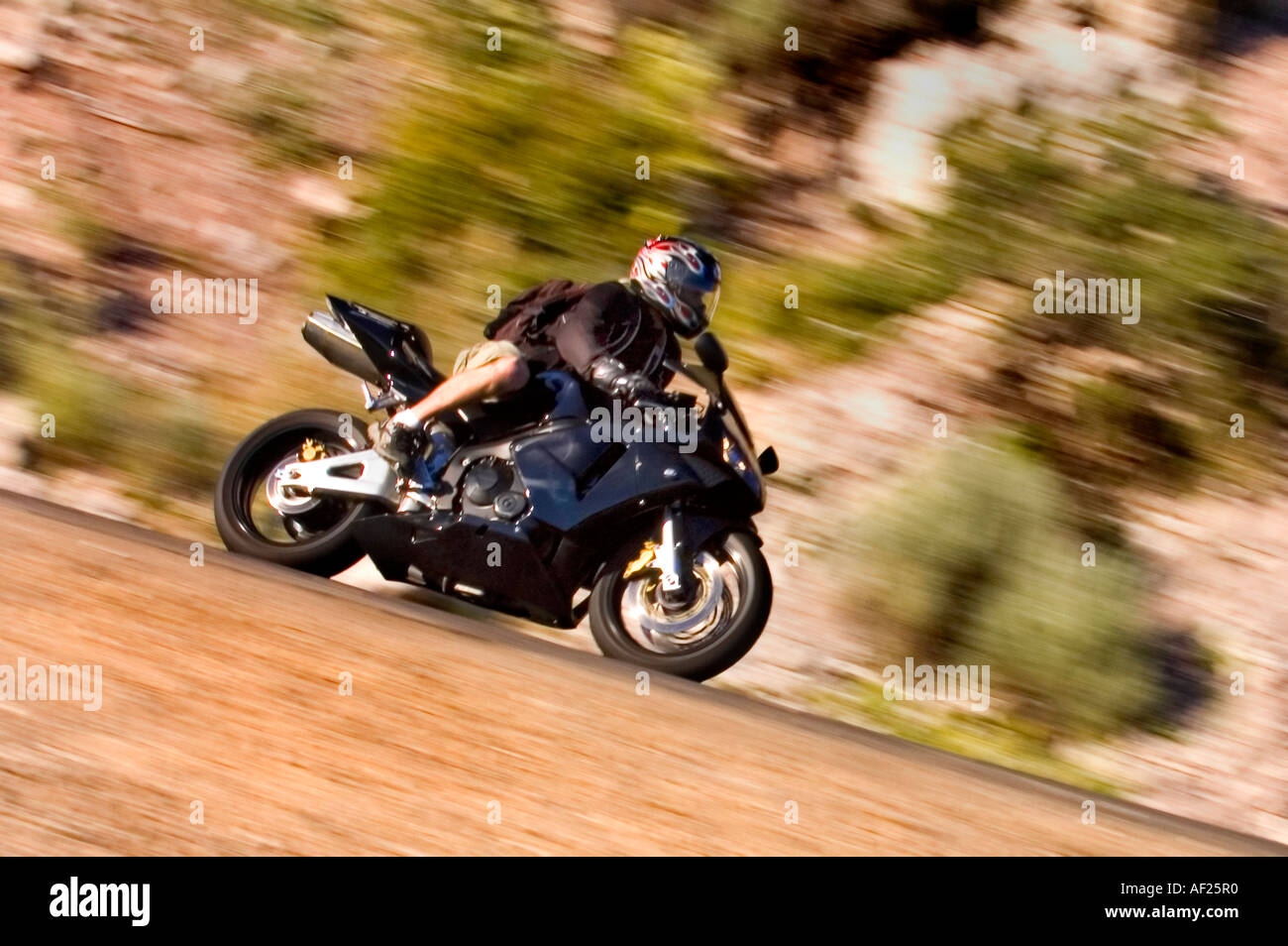 Bullet sport bike rider in shorts with a backpack on corners in a canyon Stock Photo