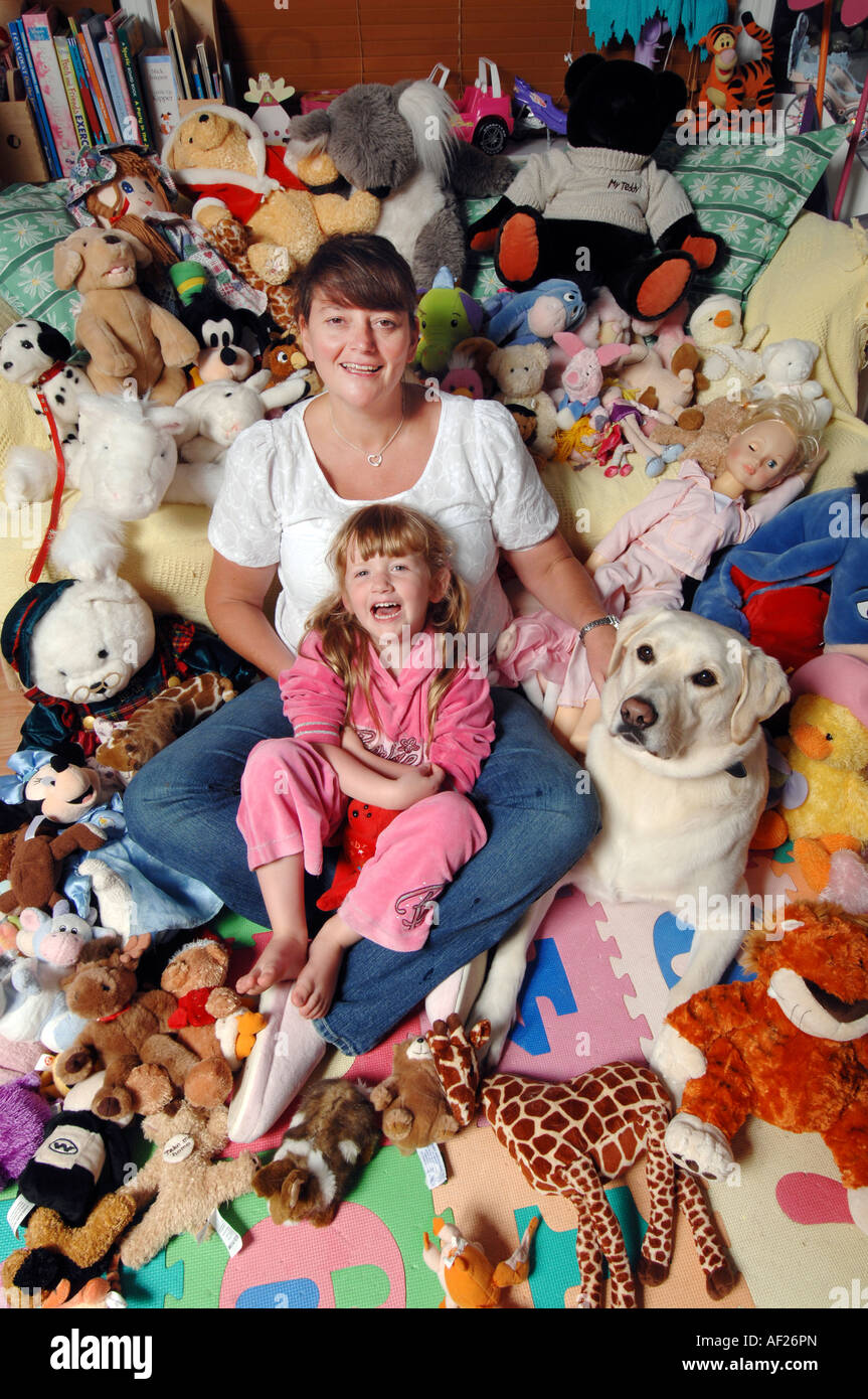 Smiling brunette mother and five year old blonde daughter with soft toys and pet dog Stock Photo
