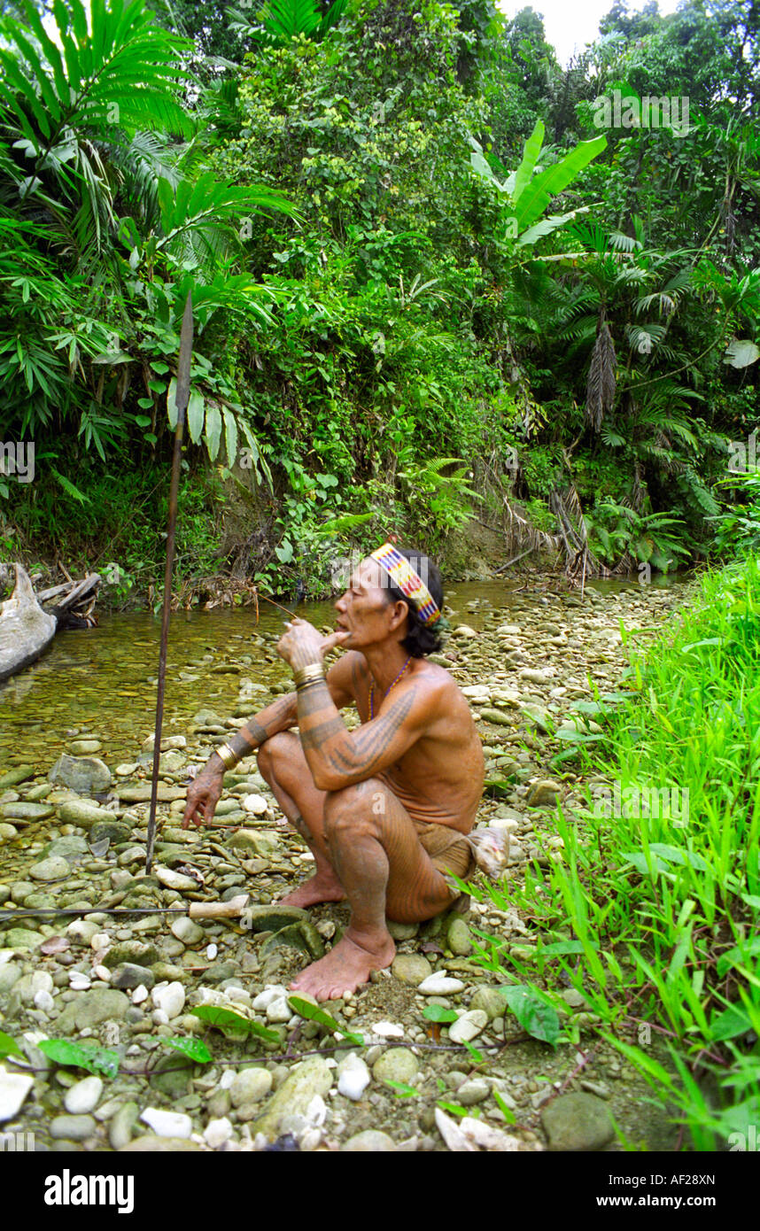 Mentawai man sitting by a stream in the forest on Siberut Island off Sumatra in Indonesia Stock Photo
