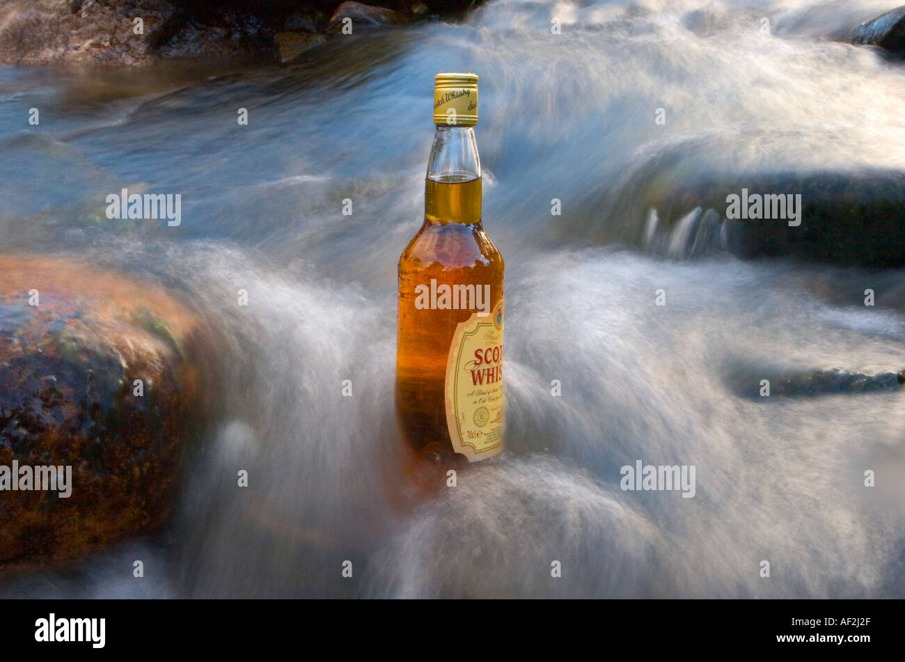 Scotch whisky bottle in ice cold water from the Cairngorms in burn near Braemar, Cairngorm National Park, Scotland, UK Stock Photo