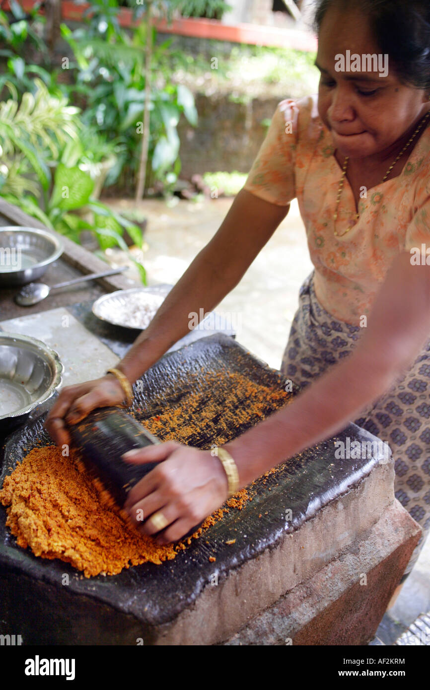 Goan Indian woman grinding coconut and chillies for curry with flat