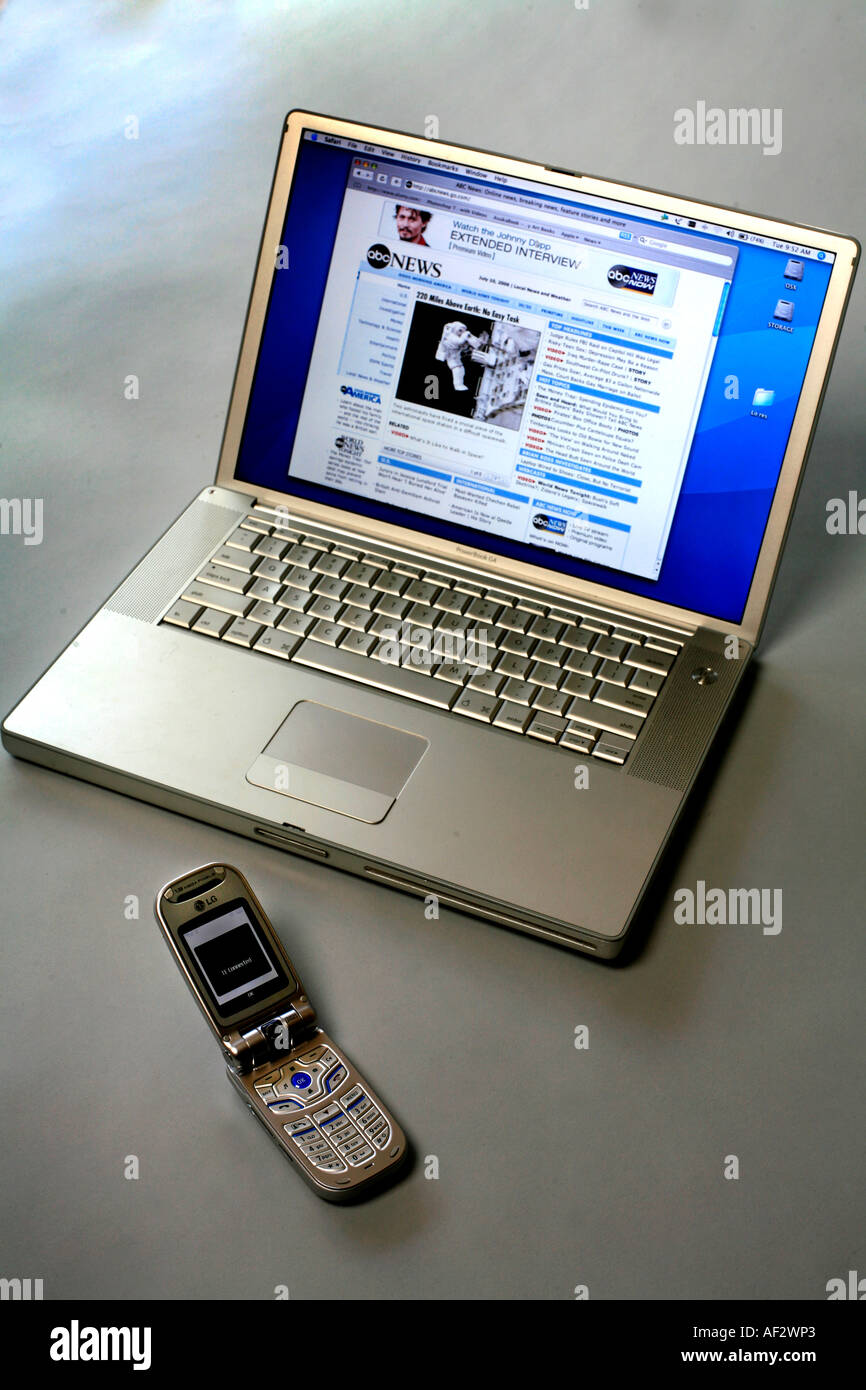 A laptop computer uses a bluetooth wireless connection to a mobile phone which  acts  as  a modem to enable access to mobile Stock Photo