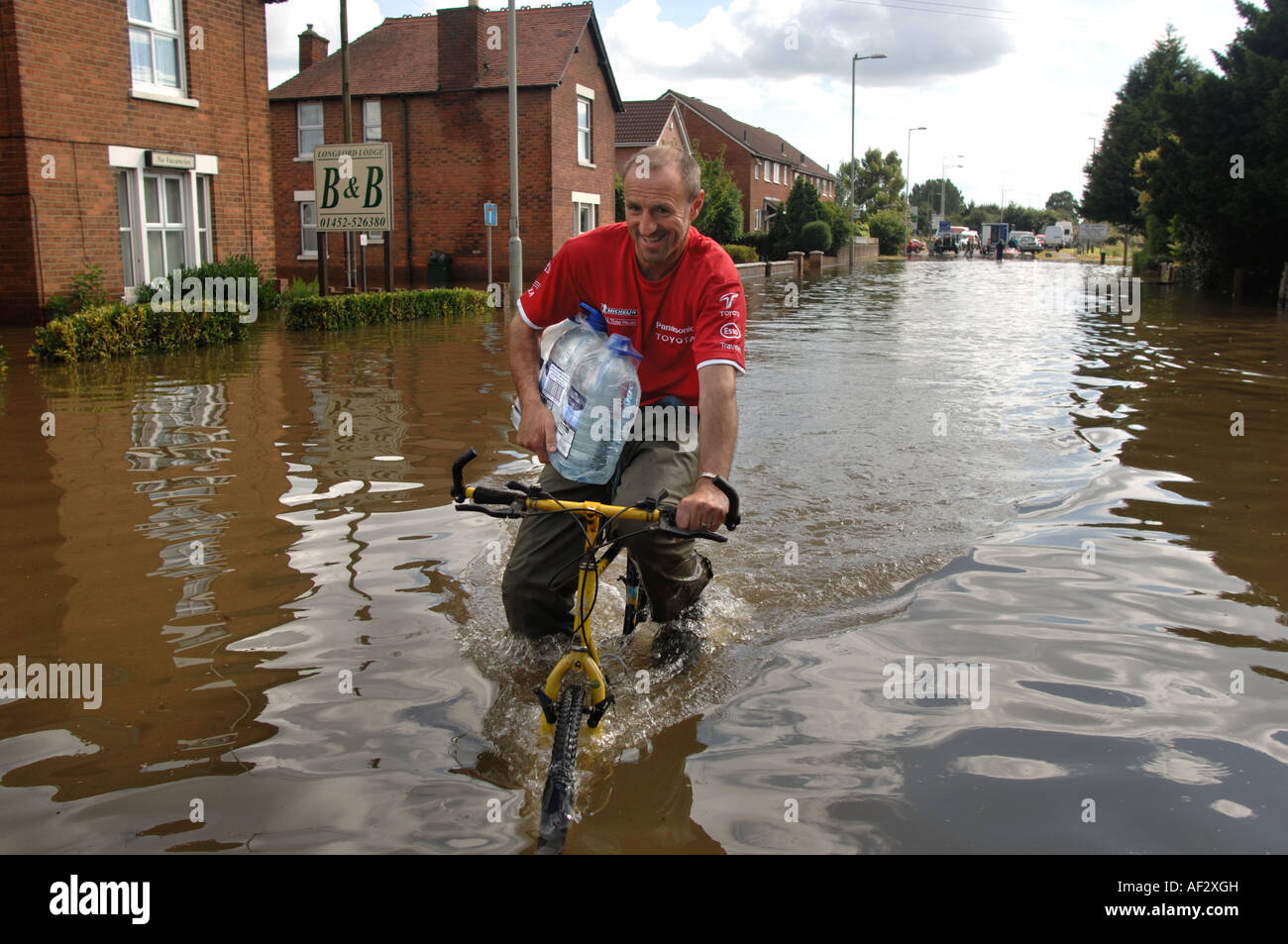Many cycling along Flooded  Road in Longford area of Gloucester carrying bottled water England July 2007 Stock Photo