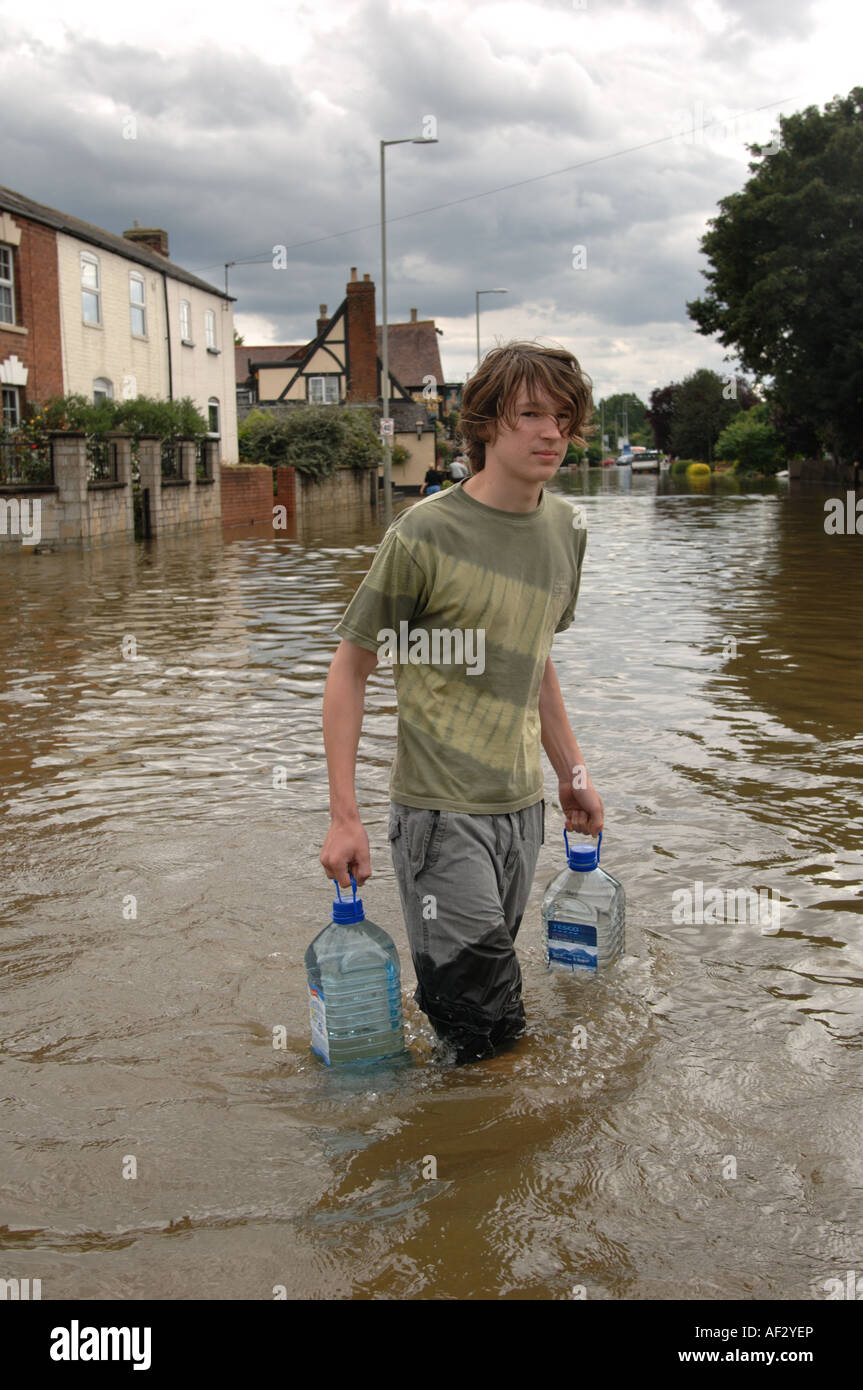 A teenager carries drinking water through floods in the Longford area of Gloucester England July 2007 Stock Photo