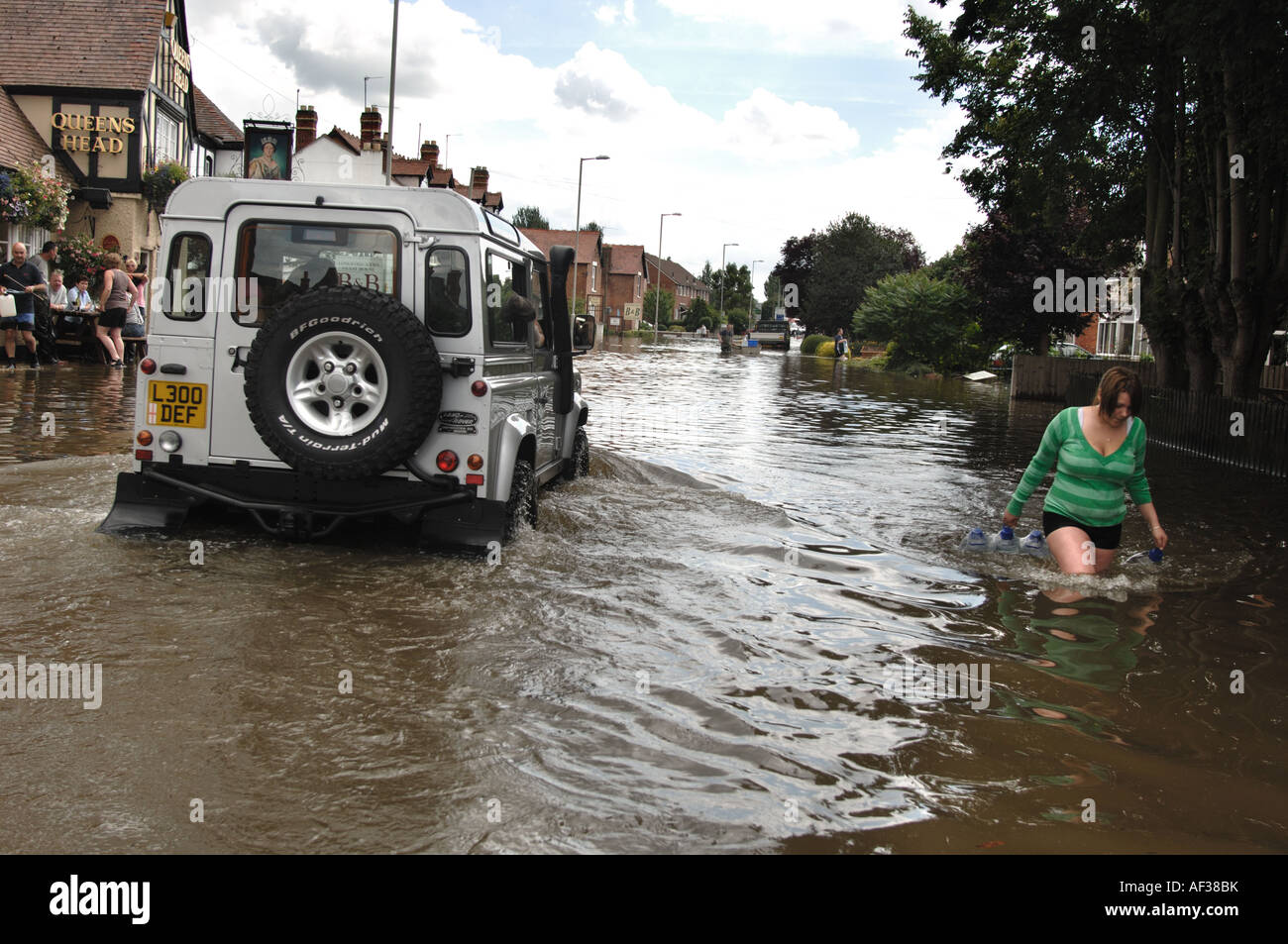 People carrying bottled water in flooded Tewkesbury Road in Longford area of Gloucester England July 2007 Stock Photo