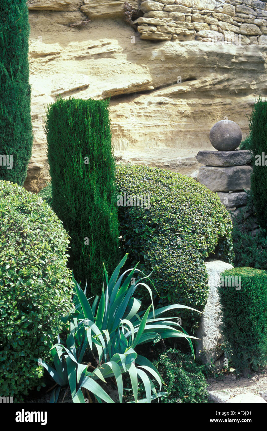 Mediterranean garden with clipped Cupressus sempervirens and Ligustrum with Astelia and Rosmarinus and stone pillar and ball  Stock Photo