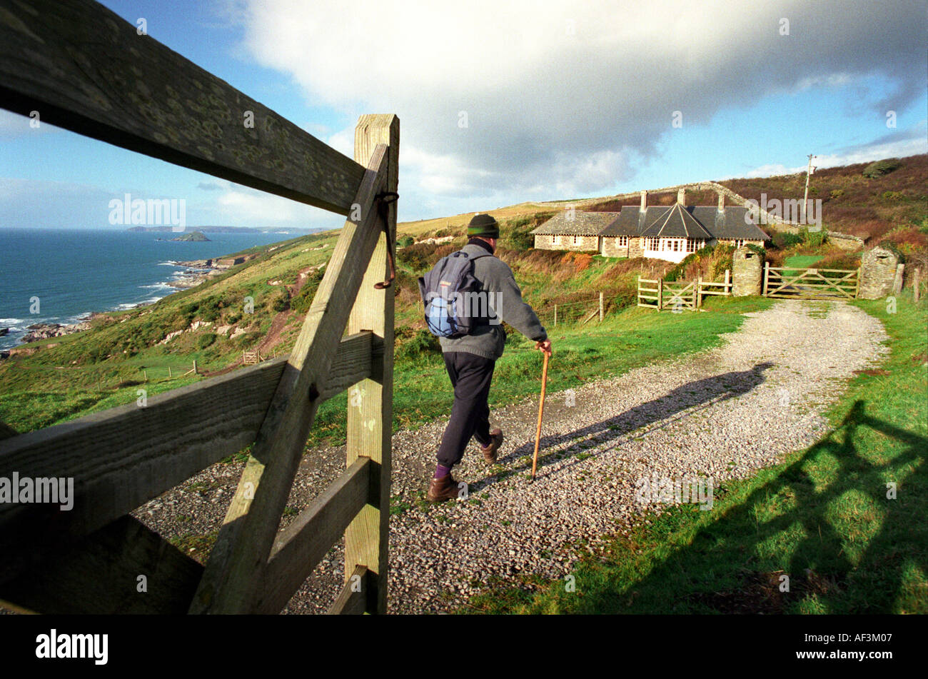 A walker strolls along the coast path near Noss Mayo in Devon UK Stock Photo