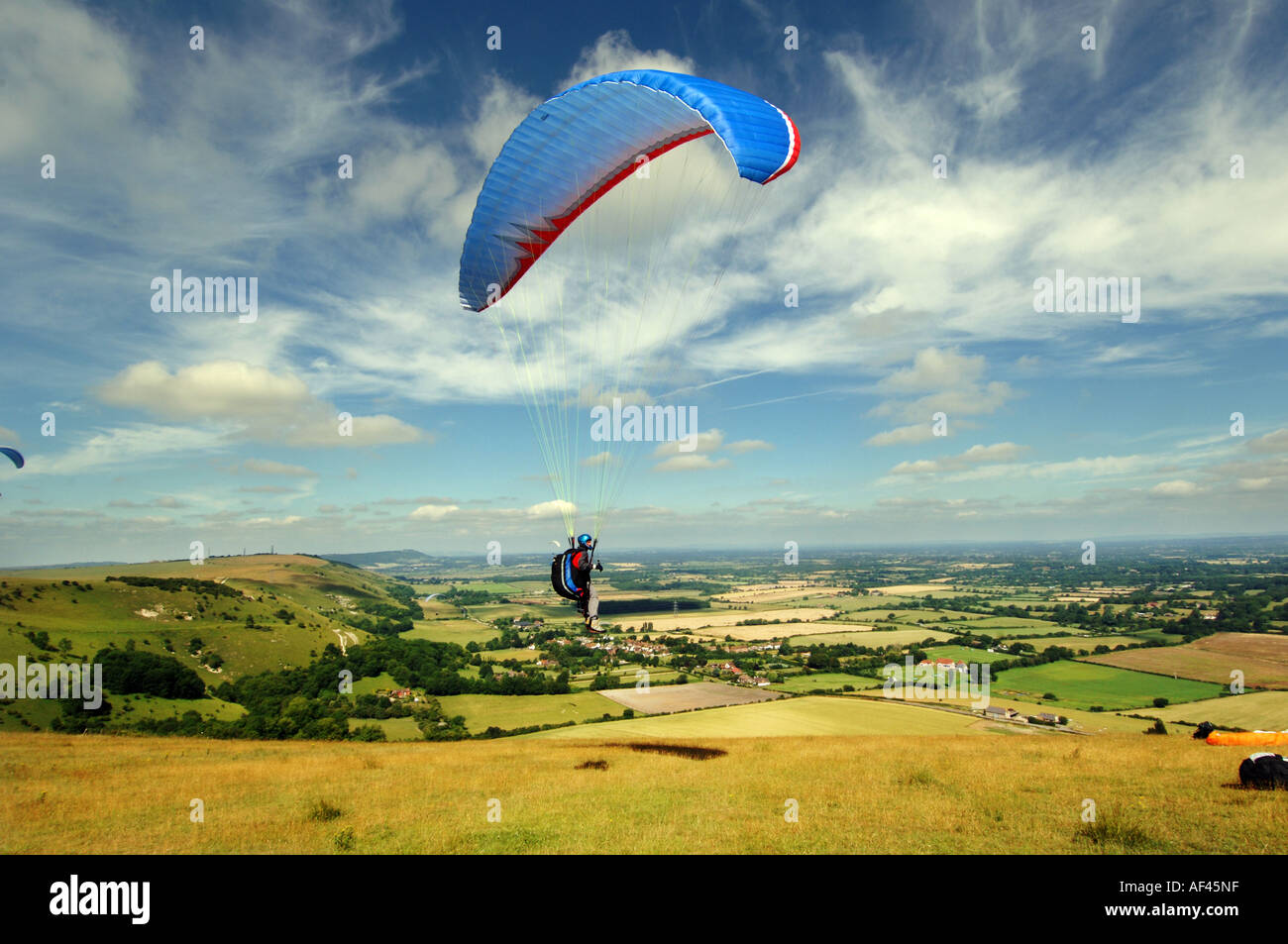 A Paraglider soars into the clouds above the South Downs at the National Trust Devils Dyke beauty spot in Sussex Stock Photo