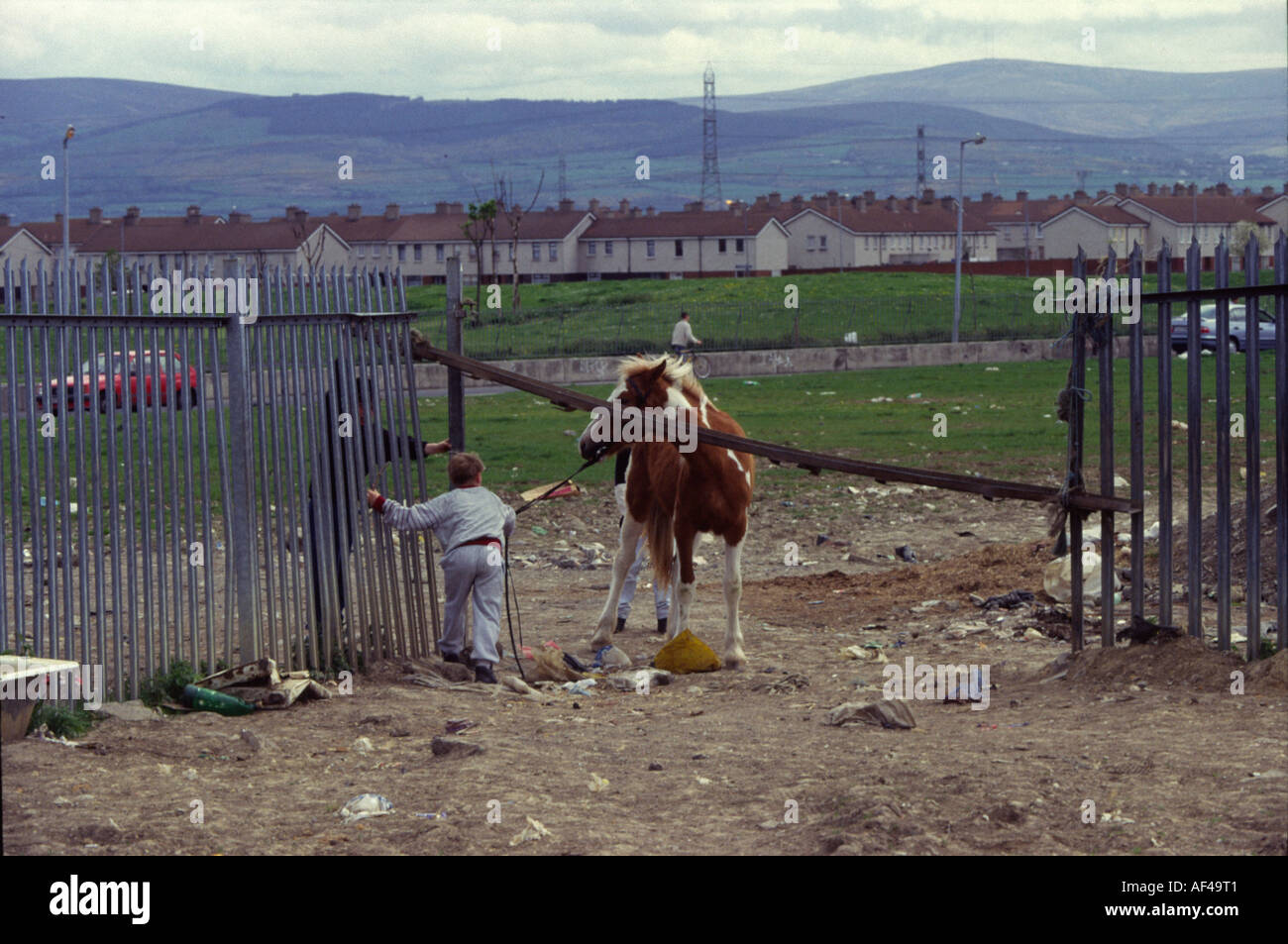 A boy tries to lead his pony under a fence on the Ballymun estate in