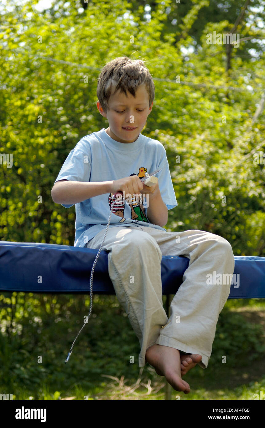 8 year old boy is sitting in the garden carving Stock Photo