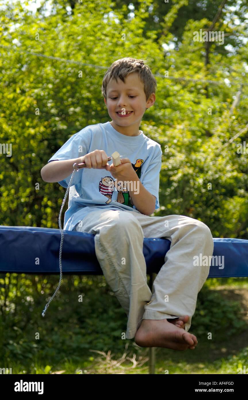 8 year old boy is sitting in the garden carving Stock Photo