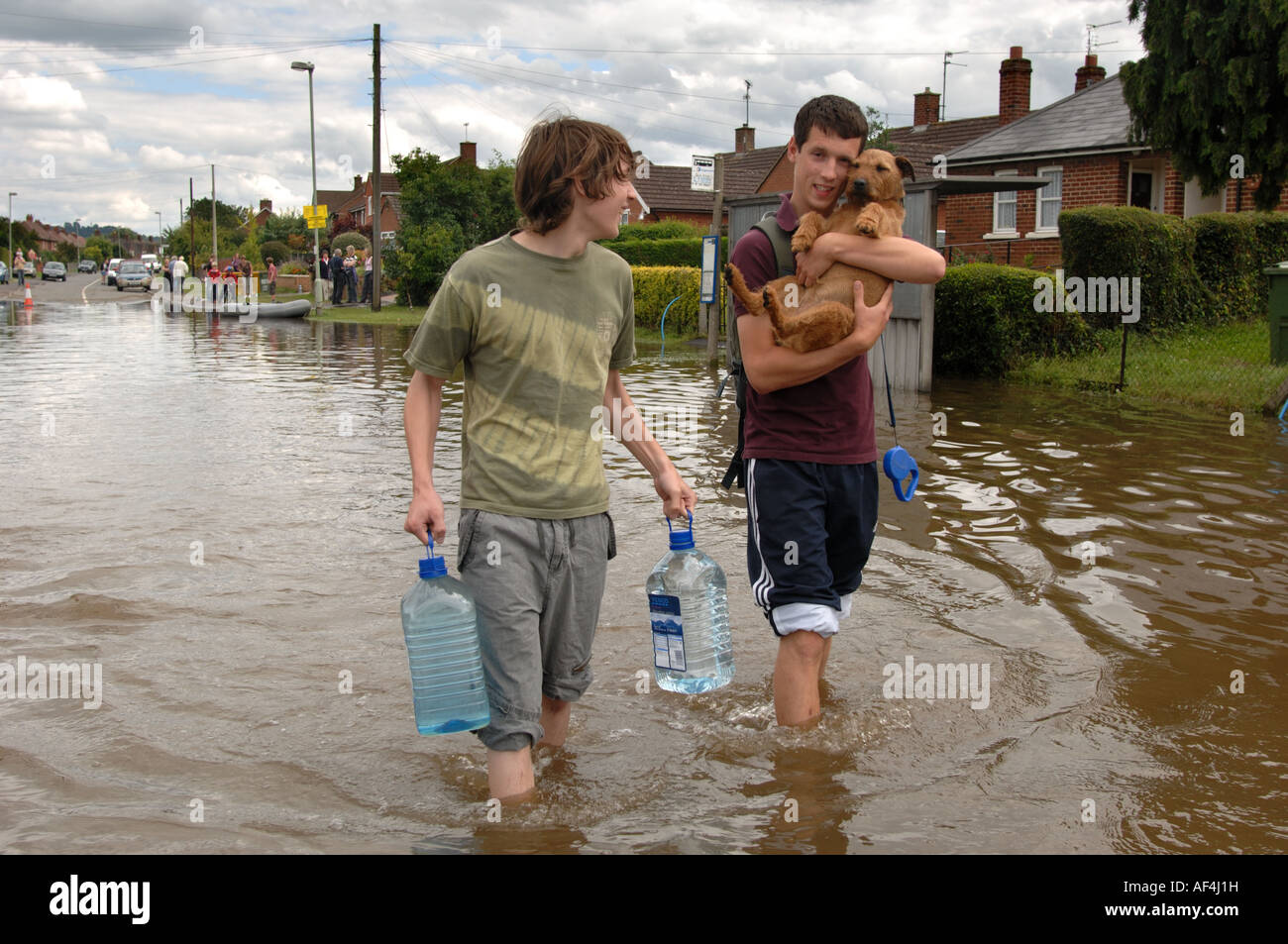Two boys with drinking water and a dog wade through the floods in the Longford area of Gloucester England July 2007 Stock Photo