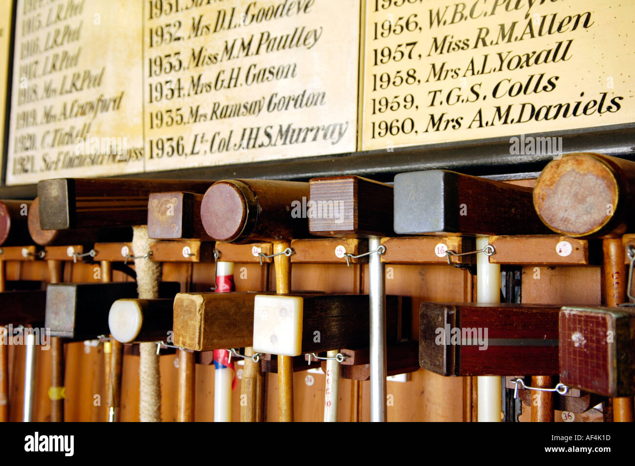 Croquet mallets hanging in a rack below championship board at