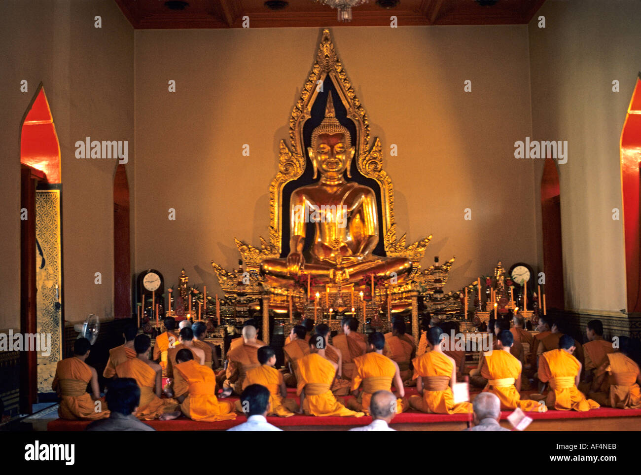 Buddhist Temple interior with lines of the backs of monks at worship ...