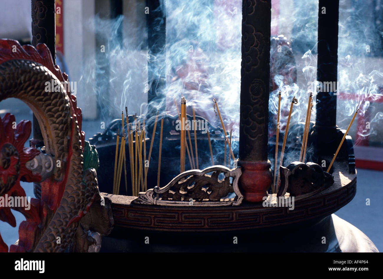 Sticks of incense burning in an urn with wreaths of blue smoke curling up at Shatin Temple Hong Kong Stock Photo
