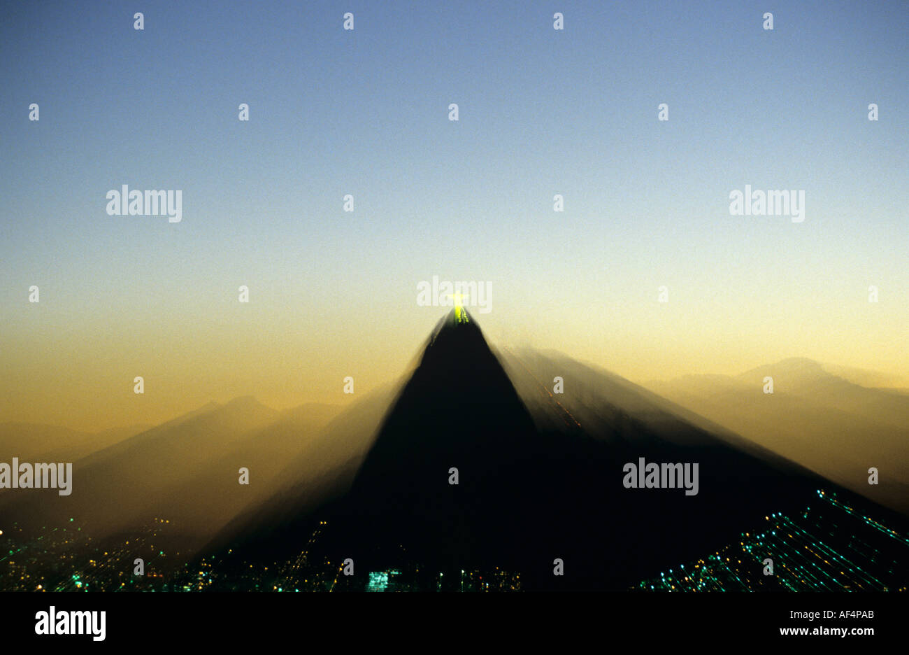 Distant zoomed view of The Corcovado at sunset with Statue of Christ illuminated Rio De Janeiro Brazil Stock Photo