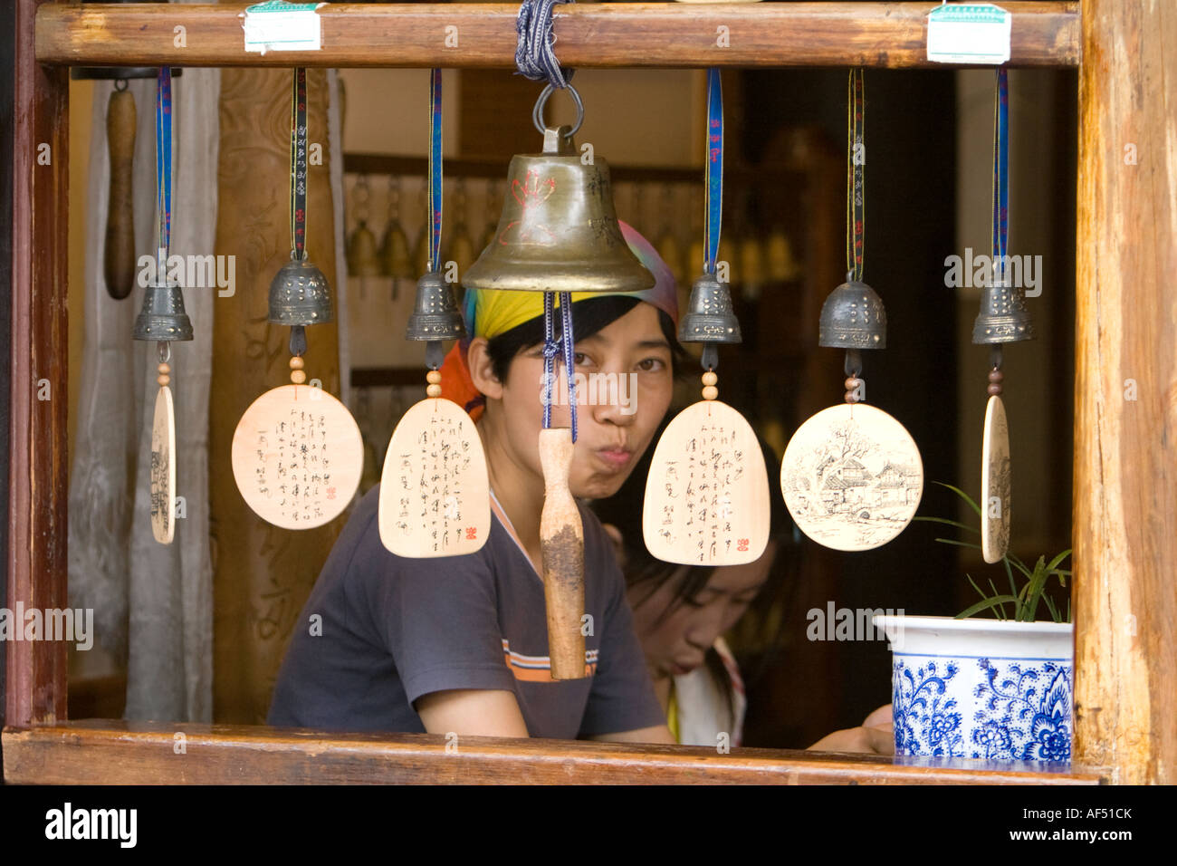 Young ethnic Naxi Chinese woman eating meal in restaurant framed by window, Lijiang Old Town, Yunnan Province, China Stock Photo
