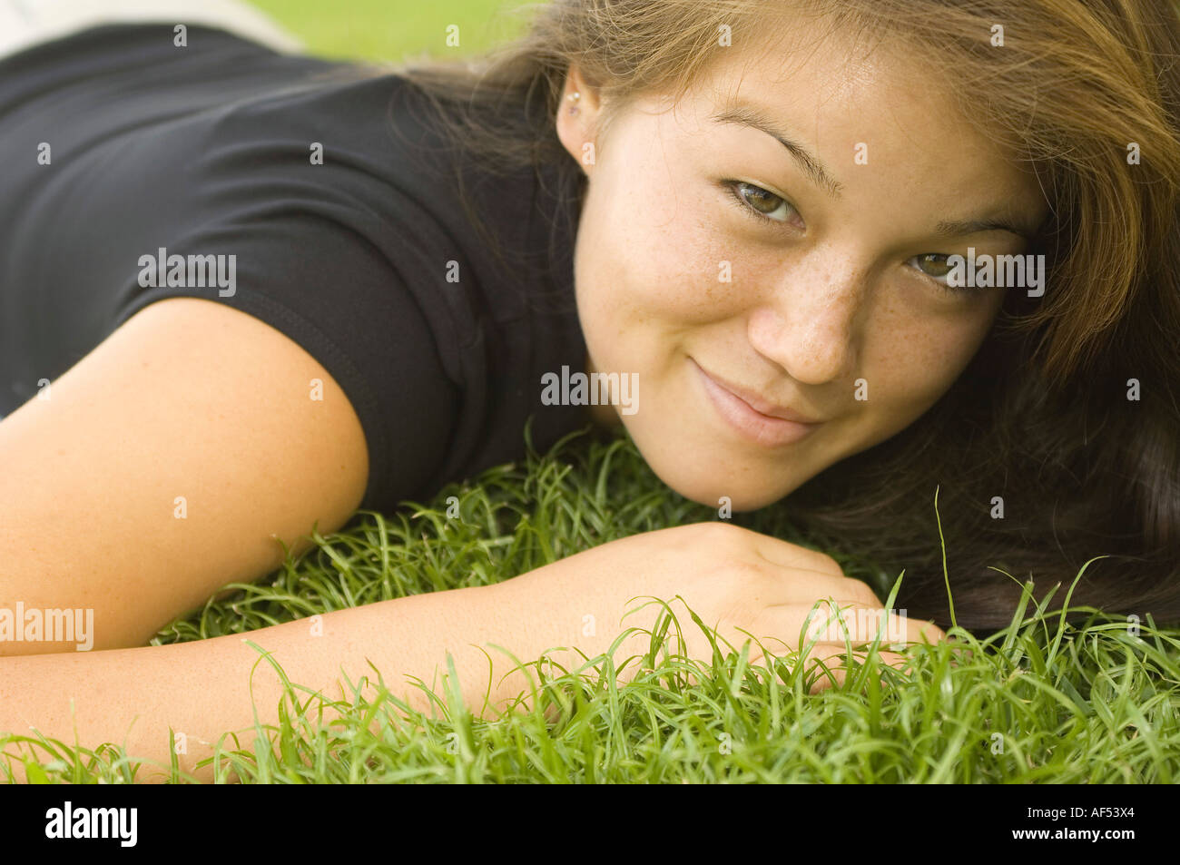 Portrait of a young woman lying on the grass Stock Photo - Alamy