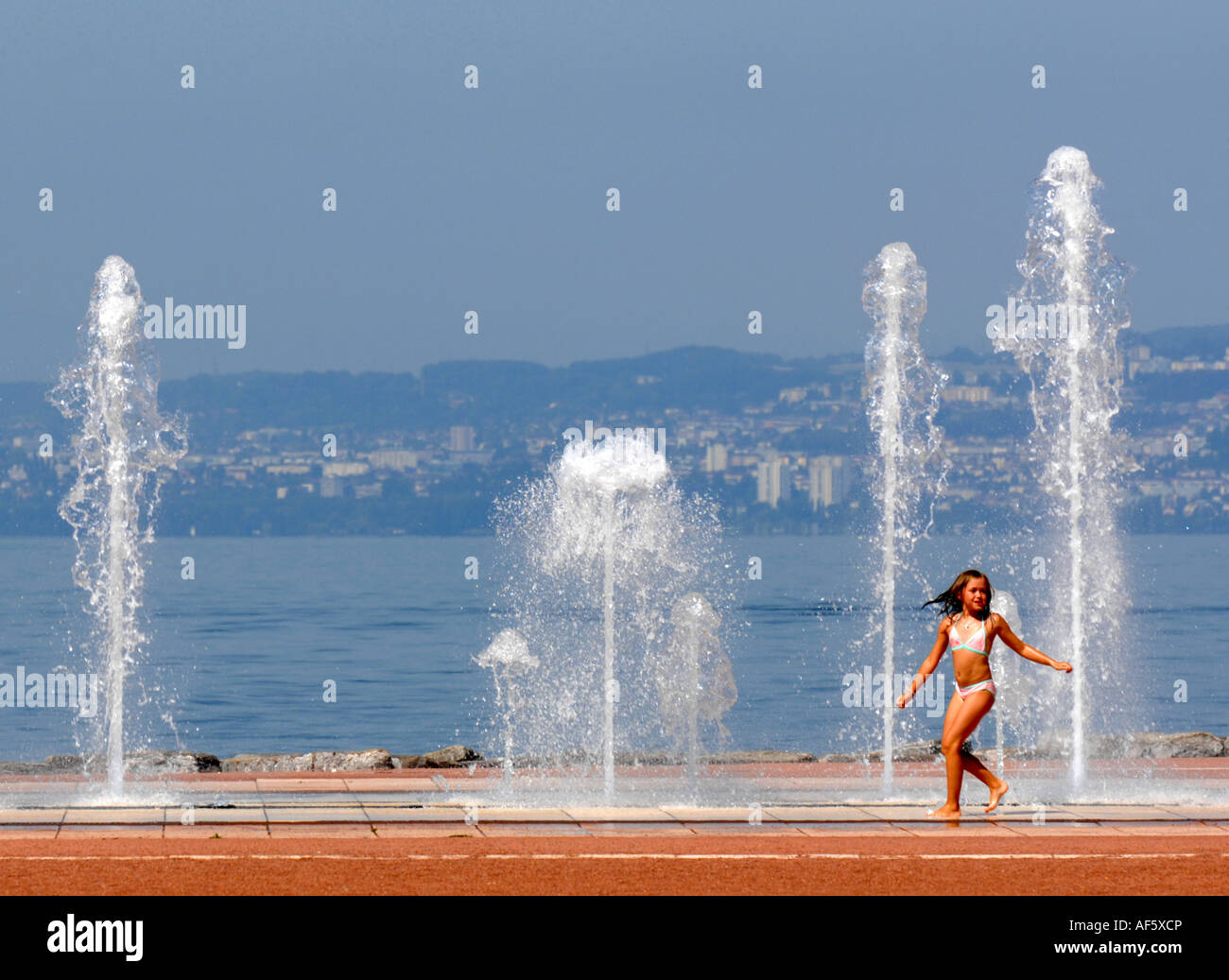 Evian, child plays in the water fountain at the side of Lake Geneva in
