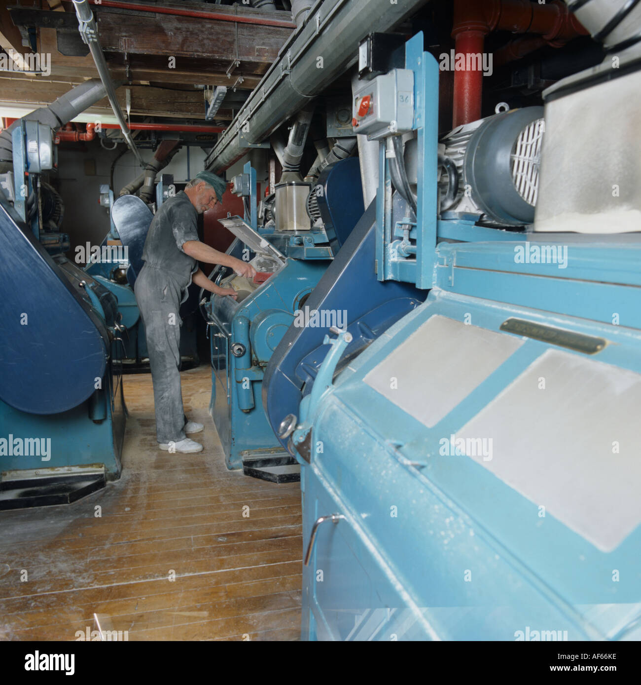 View of roller flour mills and man checking one at a flour mill Stock