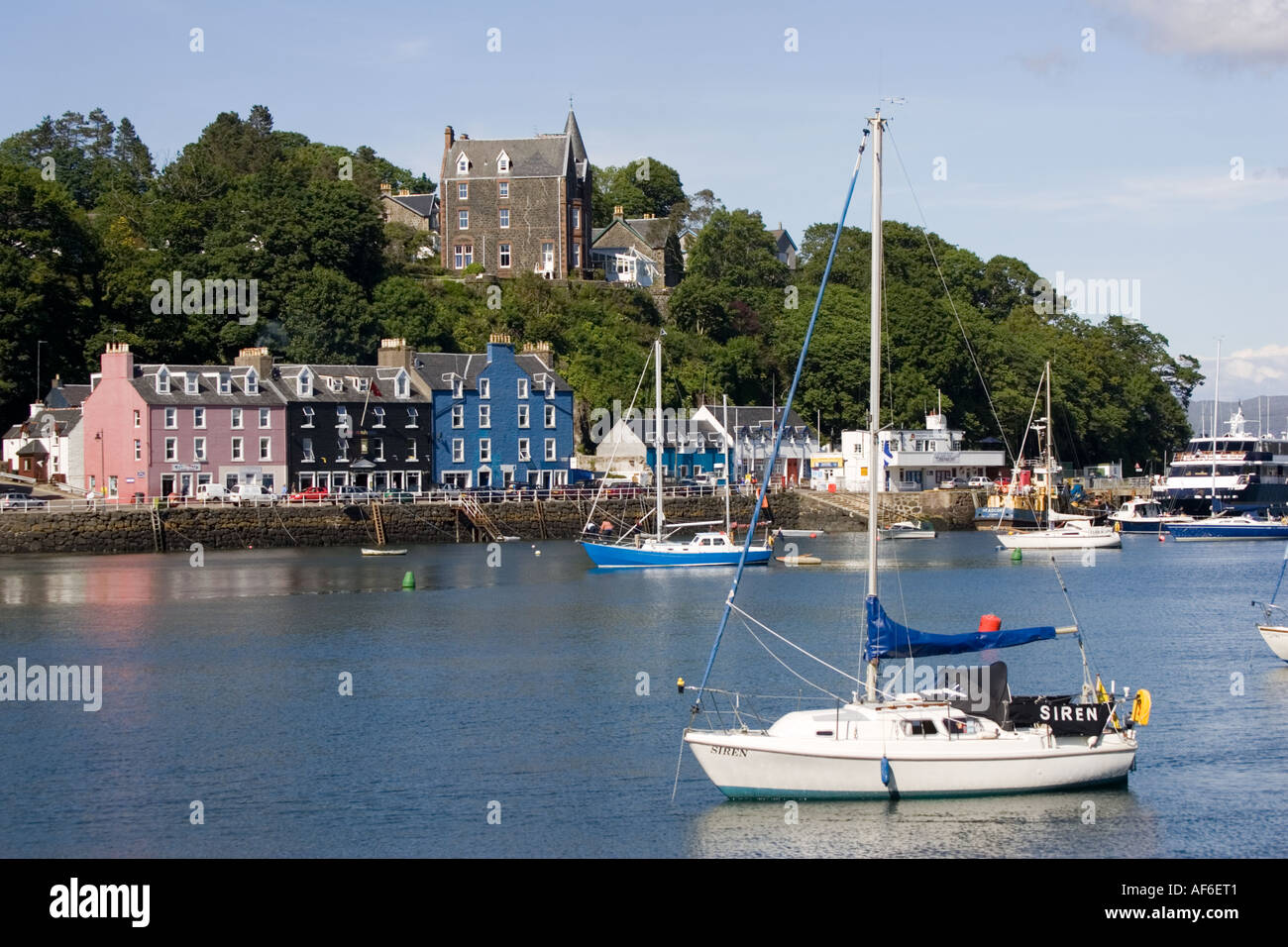 Sailing boats moored in Tobermory harbour with colourful houses along quayside Isle of Mull Scotland UK Stock Photo