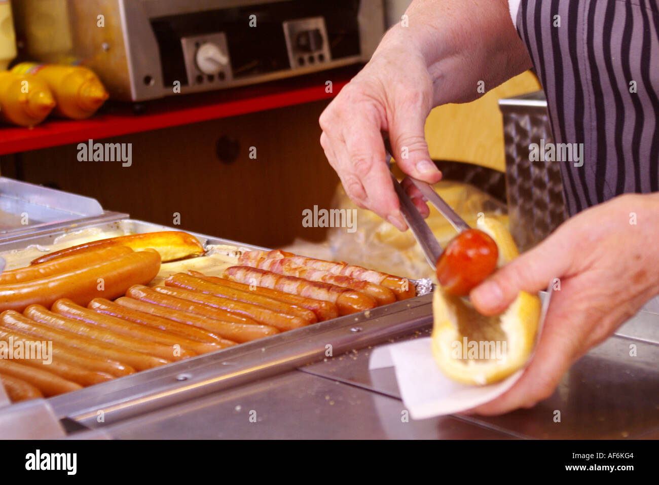 A tourist is buying a Danish hot dog on a stall in the town square in Copenhagen in Denmark Stock Photo