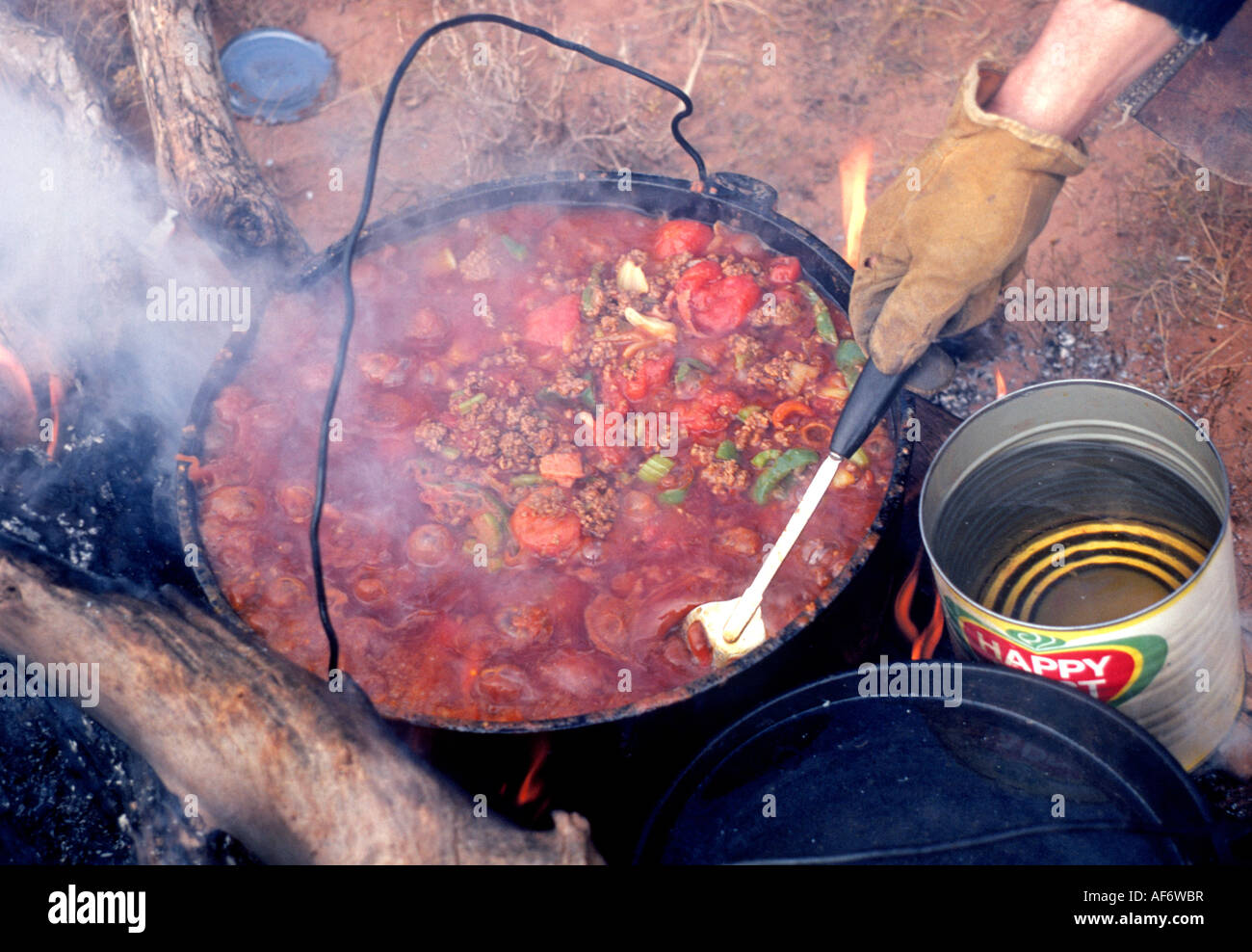 A cowboy cook prepares a cowboy chili stew over a campfire in a dutch oven  on a cattle drive on a large cattle ranch Stock Photo - Alamy
