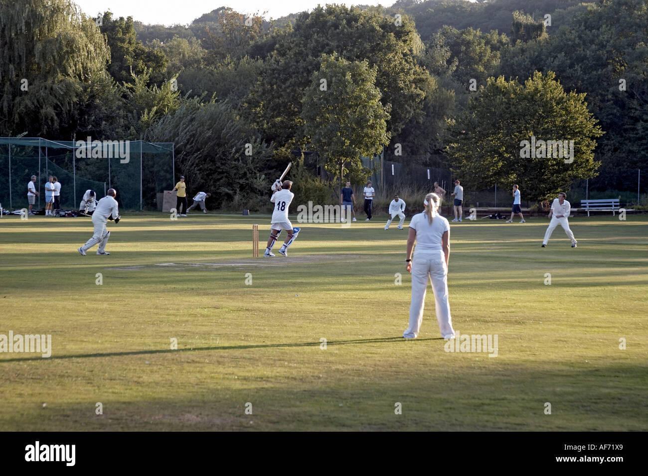 Local cricket match with Highgate Cricket Club including woman player on summer evening London
