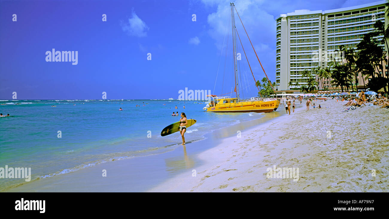 Hawaii. Honolulu. Waikiki beach with young woman carrying surfboard. Stock Photo